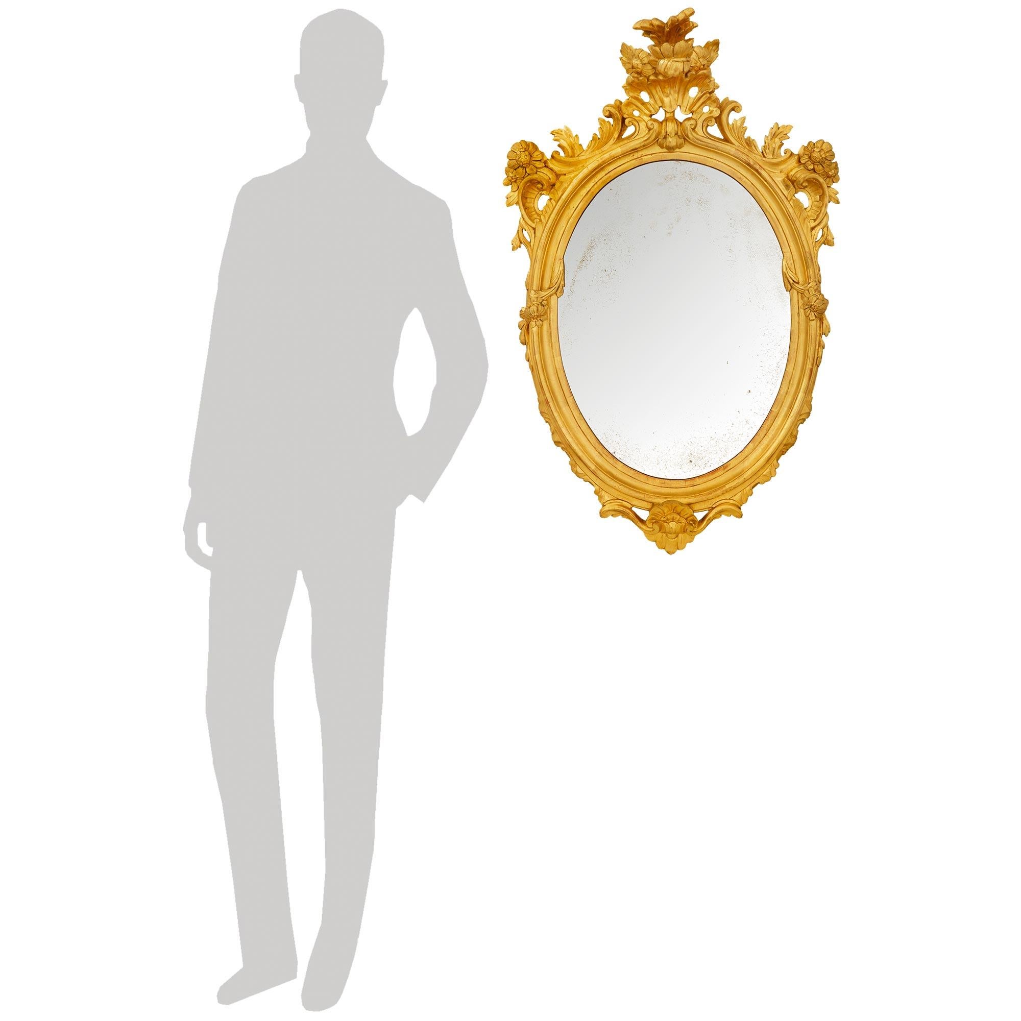 Une paire élégante et de grande qualité de miroirs baroques italiens du 19ème siècle en bois doré. Chaque superbe miroir ovale est centré en bas par une grande palmette en bois doré percée, avec des rinceaux de feuillage qui courent sur les côtés du