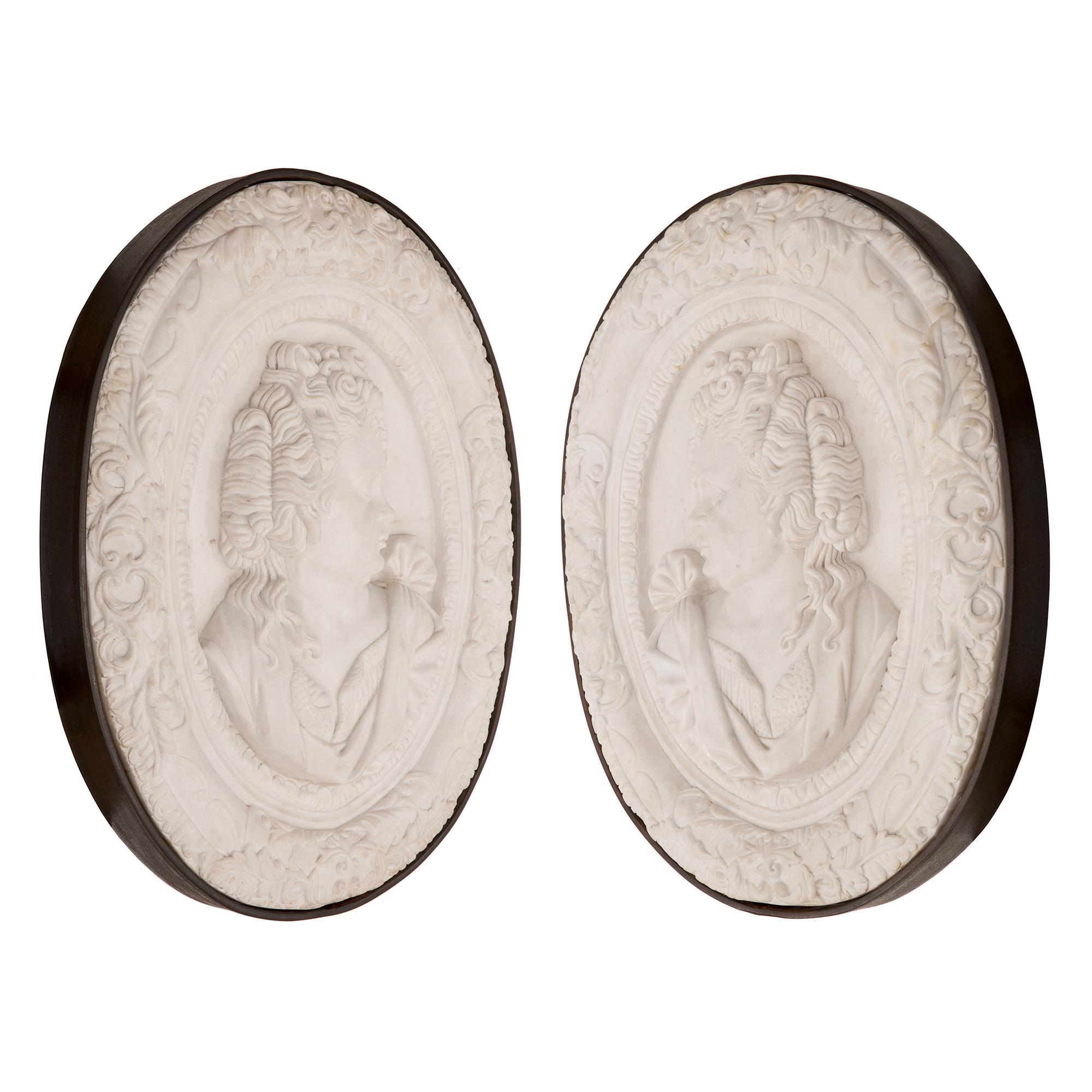 A sensational and extremely well detailed true pair of Italian 19th century white Carrara marble and iron decorative wall plaques. Each thick solid white Carrara marble plaque is framed within a fine iron border. Each central oval plaque displays a