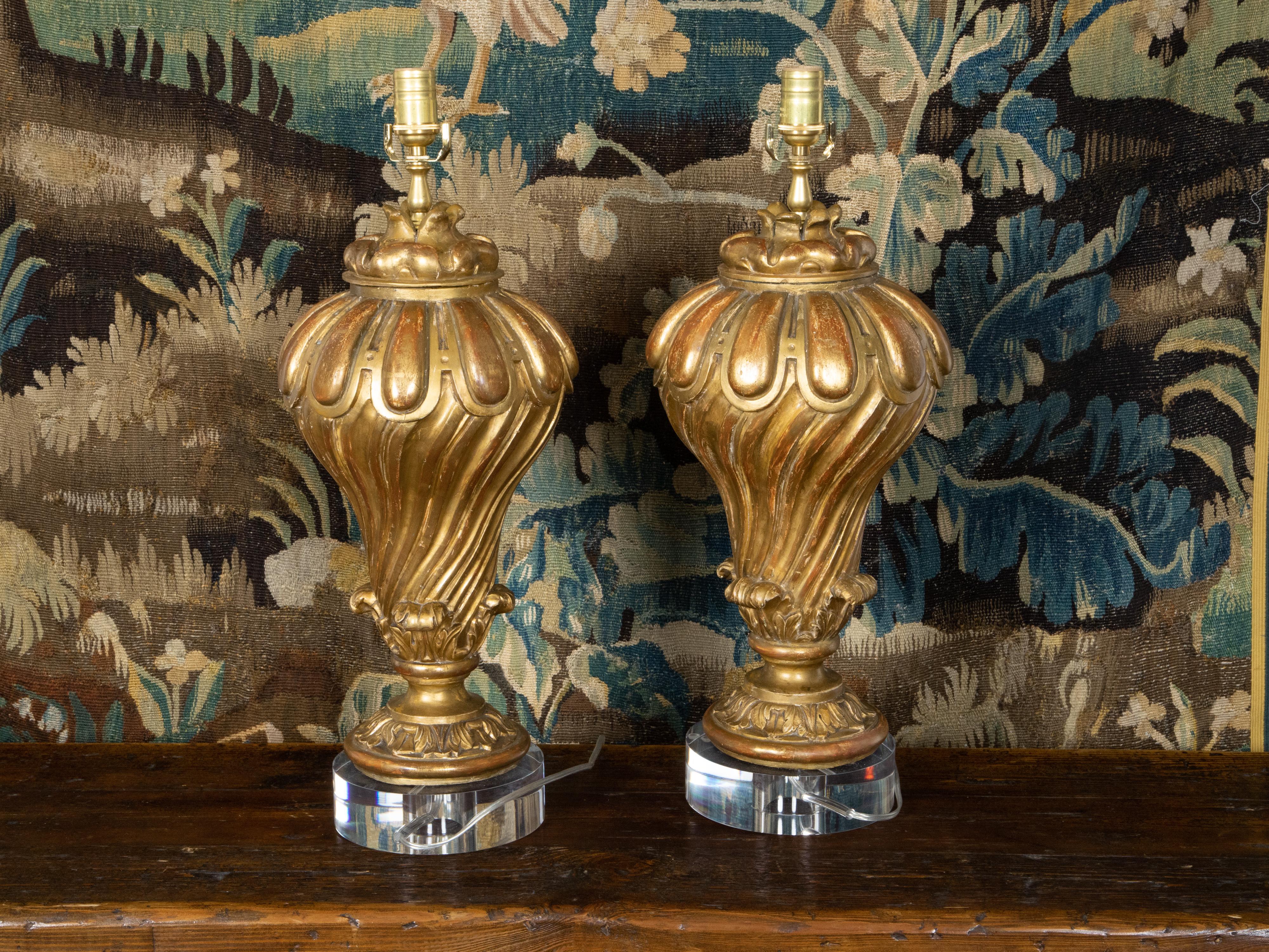 A pair of Italian carved giltwood fragments from the 19th century made into table lamps and mounted on custom lucite bases, wired for the USA. Created in Italy during the 19th century, each of this pair of fragments is made of giltwood with slight