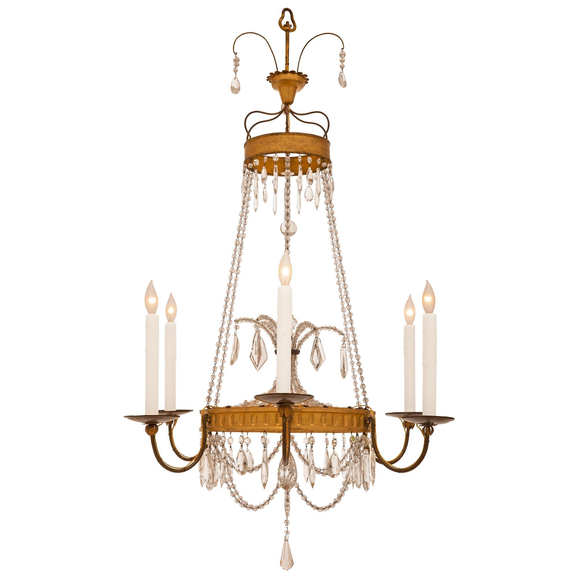 A elegant associated pair of Italian 19th century crystal, giltwood and gilt metal chandeliers. This complementary pair displays eight gilt metal arms on one, and six on the other. At the bottom of each chandelier is an elegant cut crystal pendant