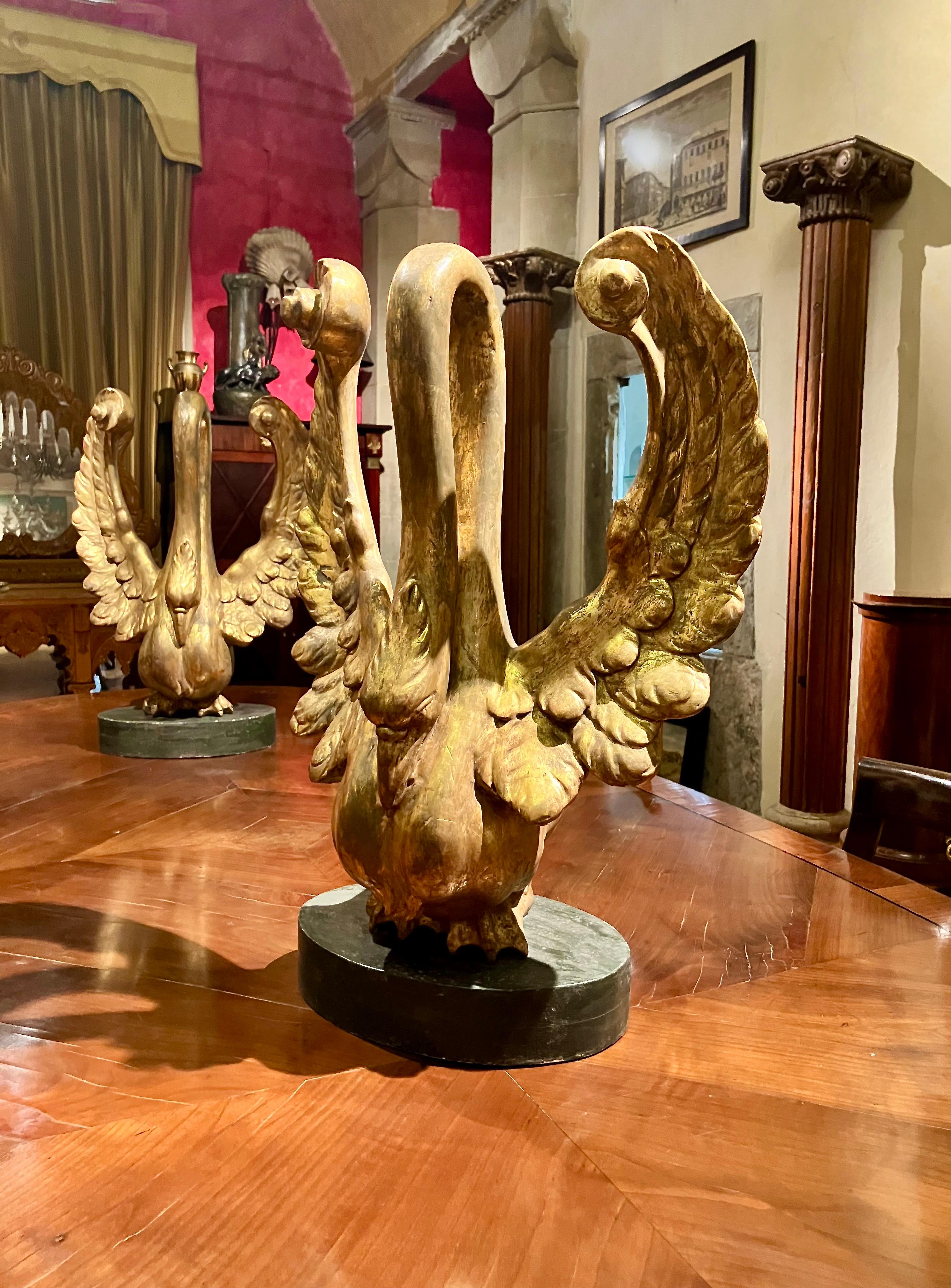 This magnificent pair of hand carved wood and gilt swans represents an extraordinary example of Italian Empire period sculptural decorative art. Masterfully crafted in Lucca, renowned for its tradition of cabinetmaking and carving, these swans