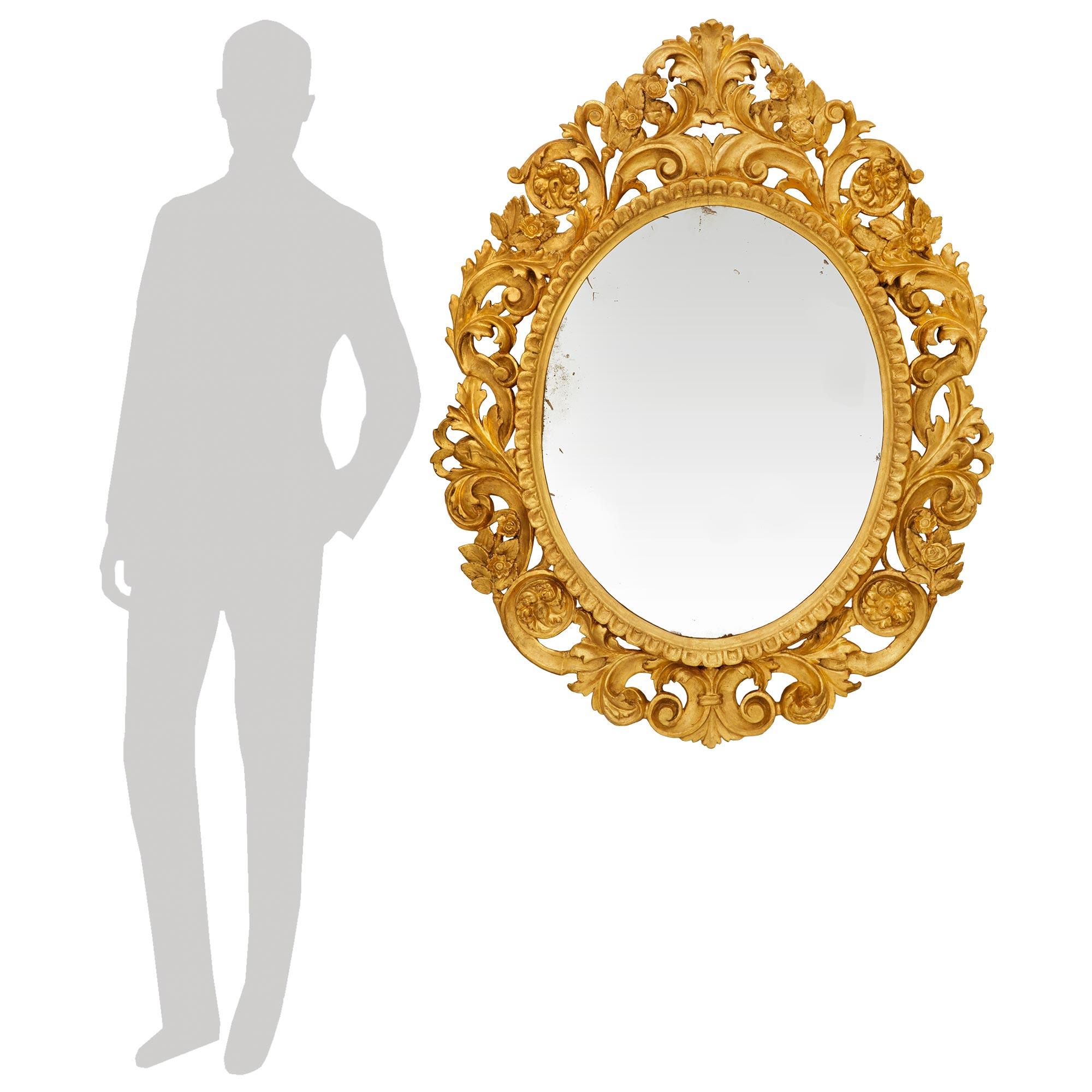Una coppia elegante e molto decorativa di specchi in legno dorato di st. Florentine del XIX secolo. Ogni splendido specchio ovale mostra le sue piastre originali rifinite con un bordo Les Oves. La cornice esterna, riccamente intagliata e traforata,