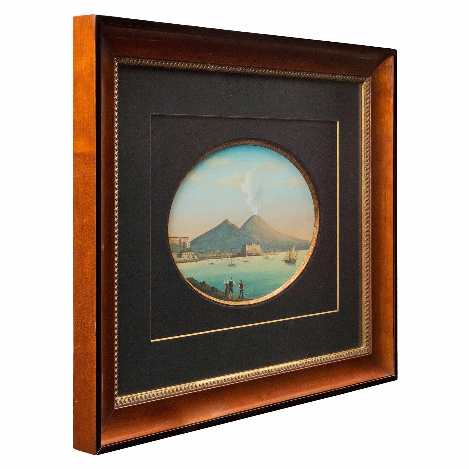 A wonderful pair of Italian 19th century gouaches depicting scenes of Naples, Italy. Each with exquisite and vibrant colors within ebony and mahogany frames with a gilt inner band. One gouache is of the Vesuvius volcano while the other is of the