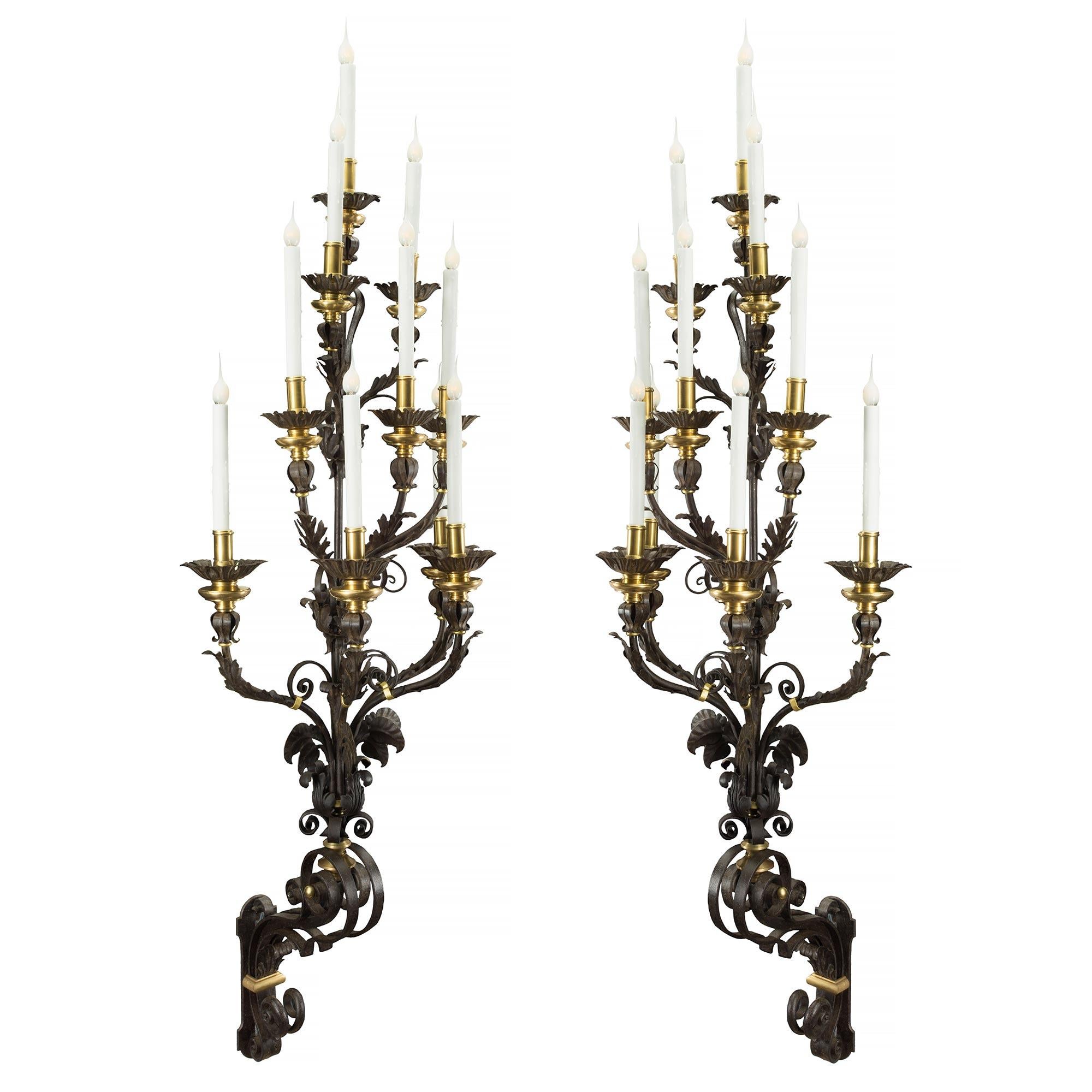 An impressive and monumentally scaled pair of Italian 19th century patinated iron, ormolu and gilt iron ten arm sconces. Each beautiful Northern Italian sconce is anchored by a decorative backplate from where large, rich, elegant scrolled arms and