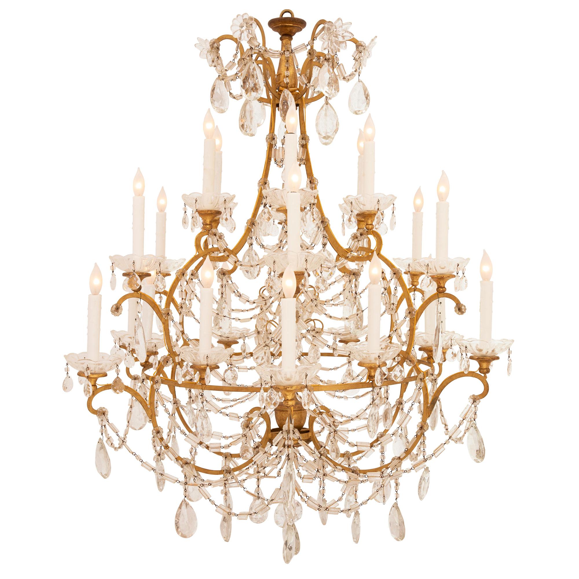 A sensational pair of Italian 19th century Louis XV st. gilt metal, giltwood, crystal and cut glass chandeliers. Each most impressive twenty four light chandelier is centered by a stunning array of most decorative cut crystal pendants amidst