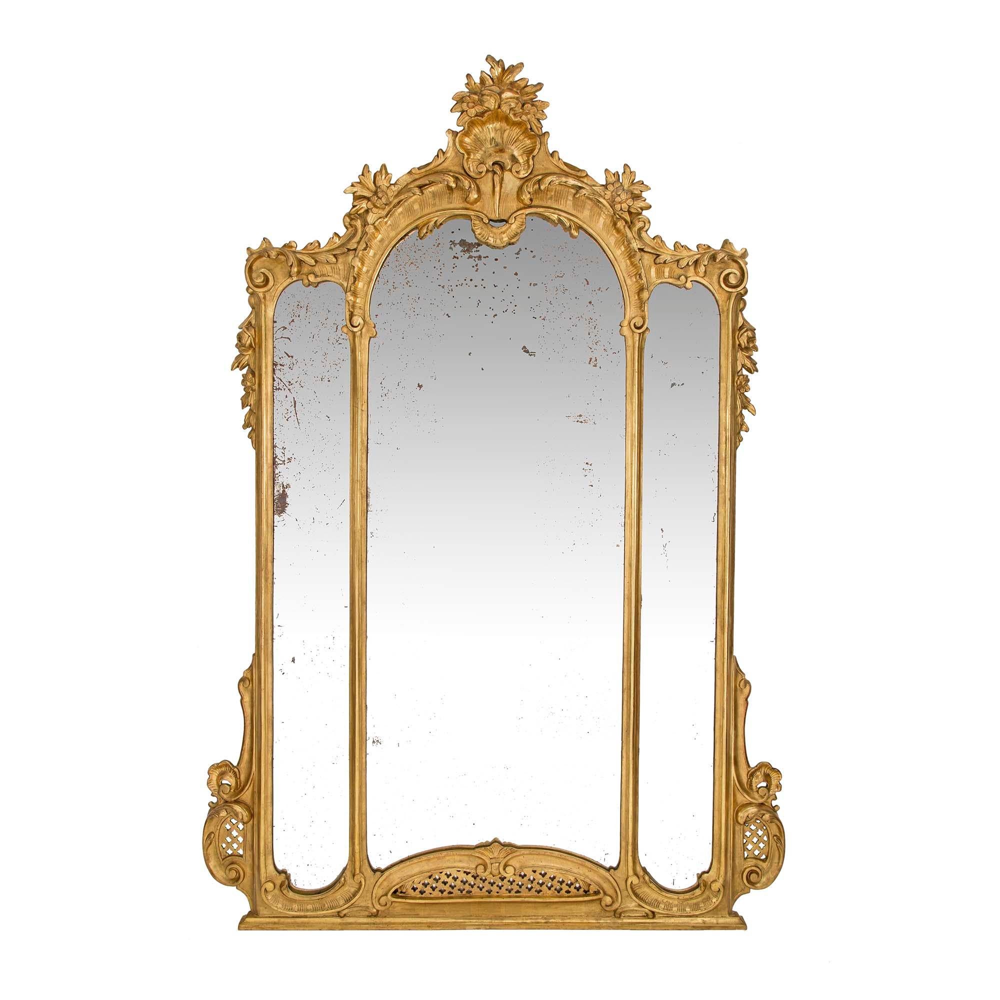 A handsome and large scale pair of Italian 19th century Louis XV st. giltwood mirrors. Each mirror has three mirror plates within the double frame. At the straight base are lovely foliate scrolls and a pierced rosette design repeated at each side.