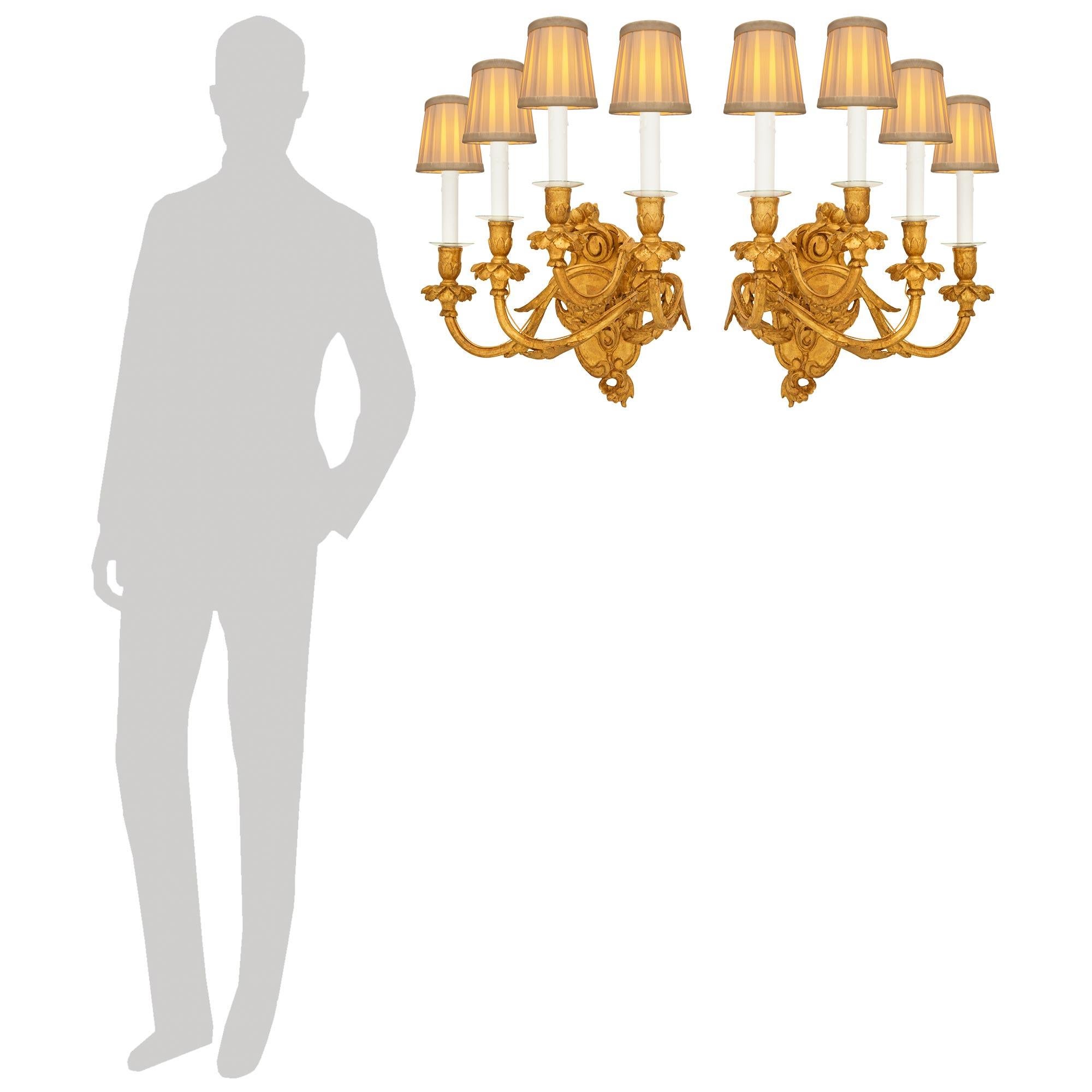 Ein elegantes Paar italienischer Kronleuchter aus Giltwood im Stil Louis XV des 19. Jeder der atemberaubenden vierarmigen Wandleuchter steht auf einer wunderschön geschnitzten, wappenförmigen Giltwood-Rückwand mit Rocaille-Bewegungen und