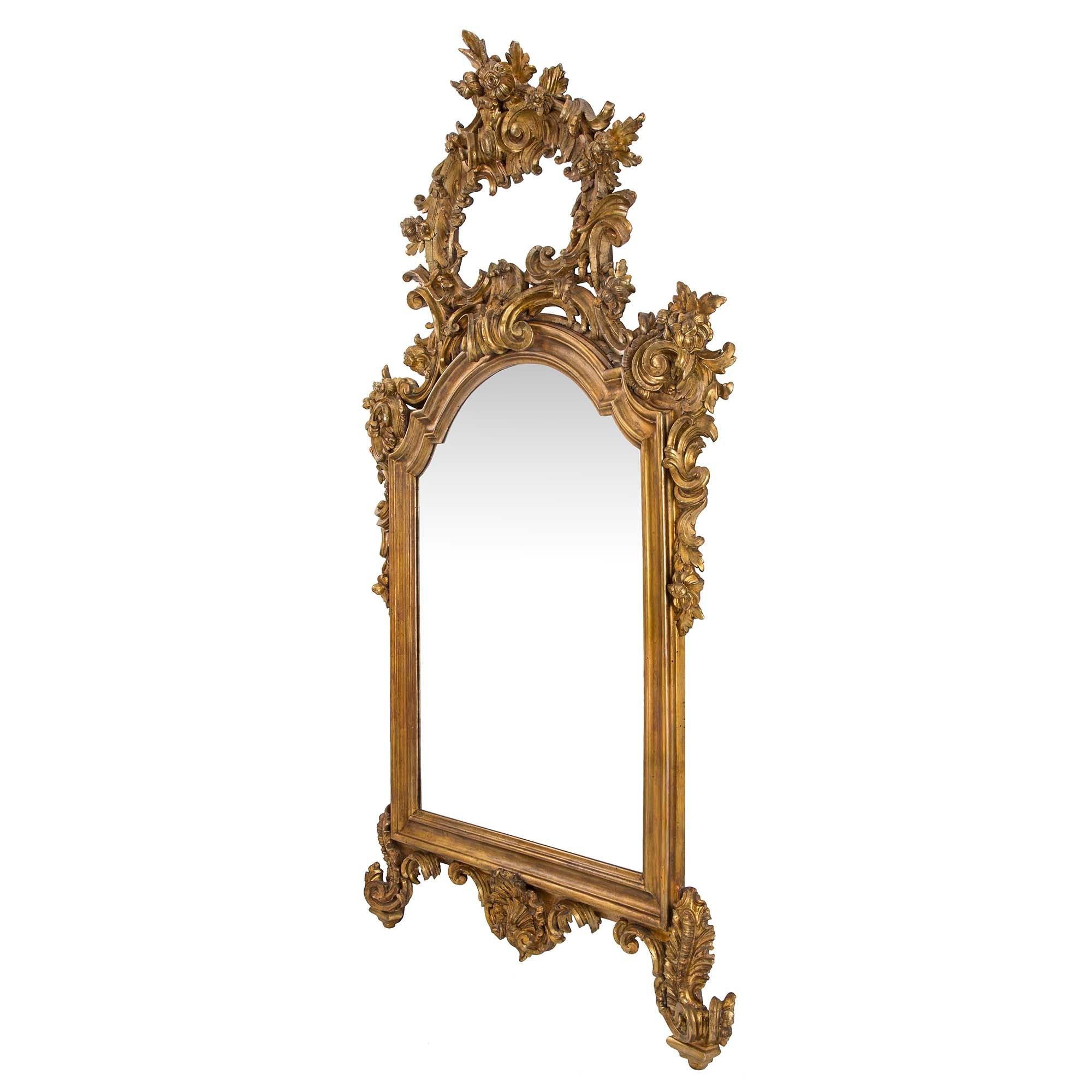 A magnificent pair of Italian 19th century Louis XV st. finely carved mecca mirrors. Each mirror is raised by most elegant and richly carved scrolled foliate feet centering a fine seashell reserve. At the center are the original mirror plated framed