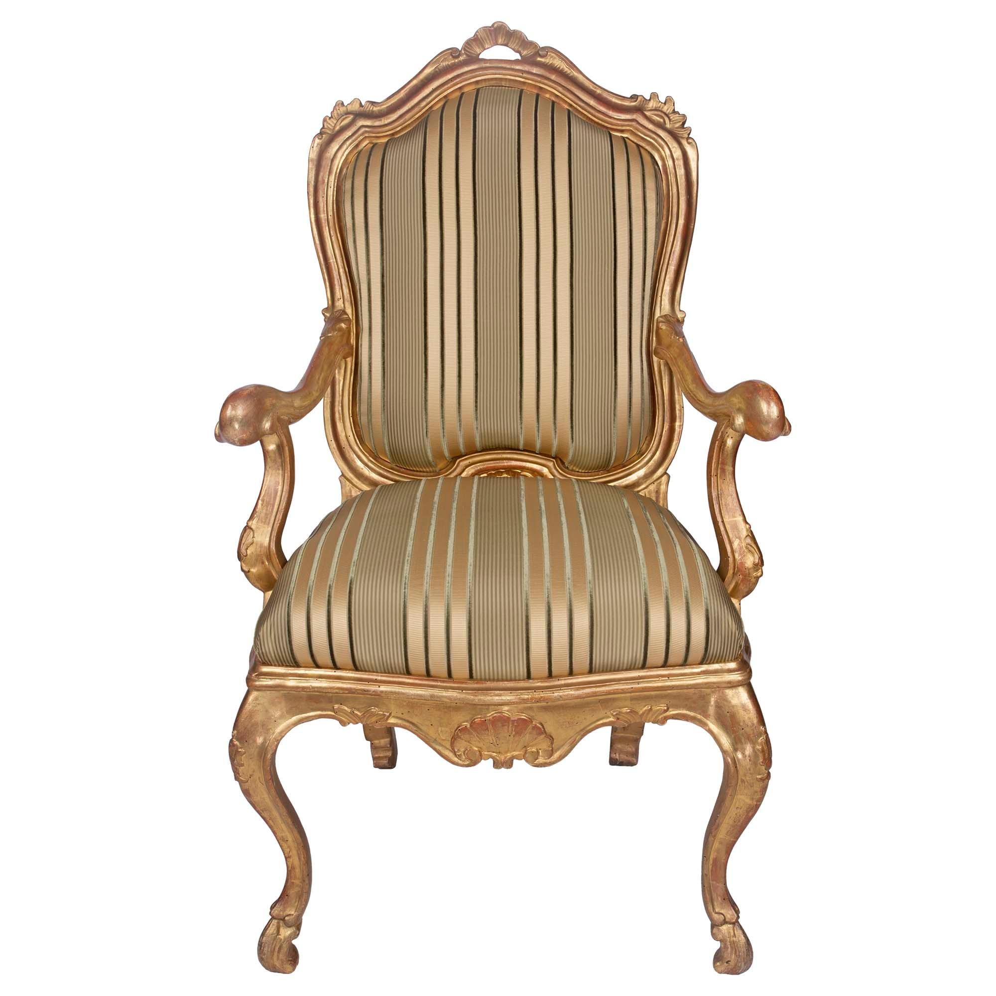 A striking pair of Italian 19th century Louis XV st. giltwood armchairs à Chassis. Each upholstered armchair, à Chassis, which signifies that the upholstery is easily removed and changed for every season, is raised by fine cabriole legs ending in
