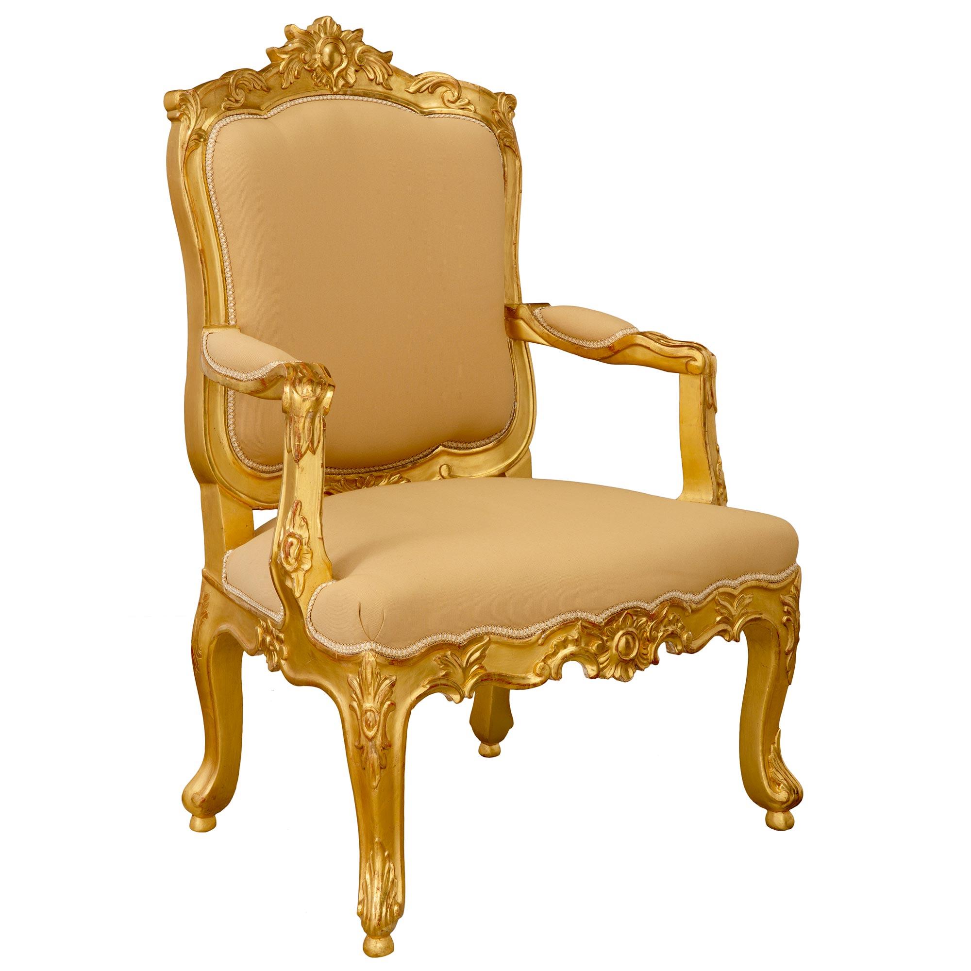A wonderful pair of Italian 19th century Louis XV st. giltwood armchairs. Each chair is raised by elegant cabriole legs with large richly carved acanthus leaves and beautiful floral reserves at each corners. The aprons display most decorative