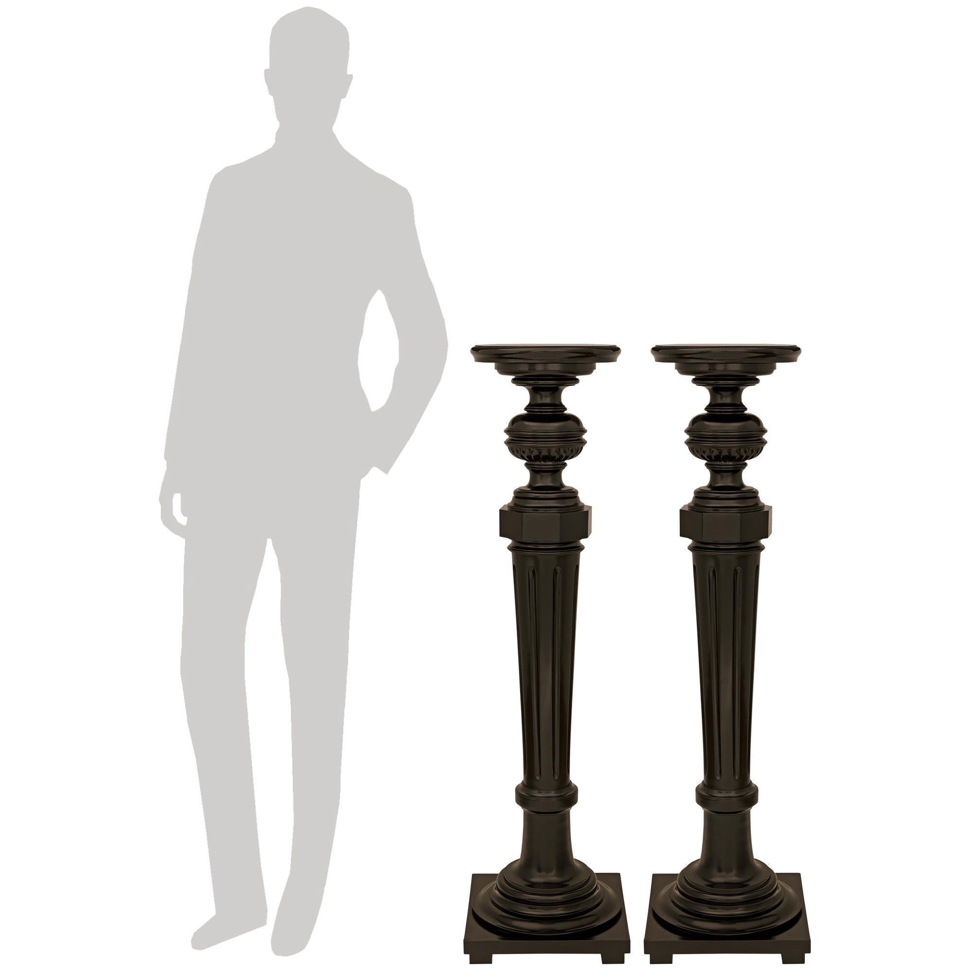 A most elegant pair of Italian 19th century Louis XVI st. ebonized Fruitwood pedestals. Each handsome pedestal is raised by an elevated square plinth supporting a circular socle leading up to a hand carved fluted and tapered column capped by an