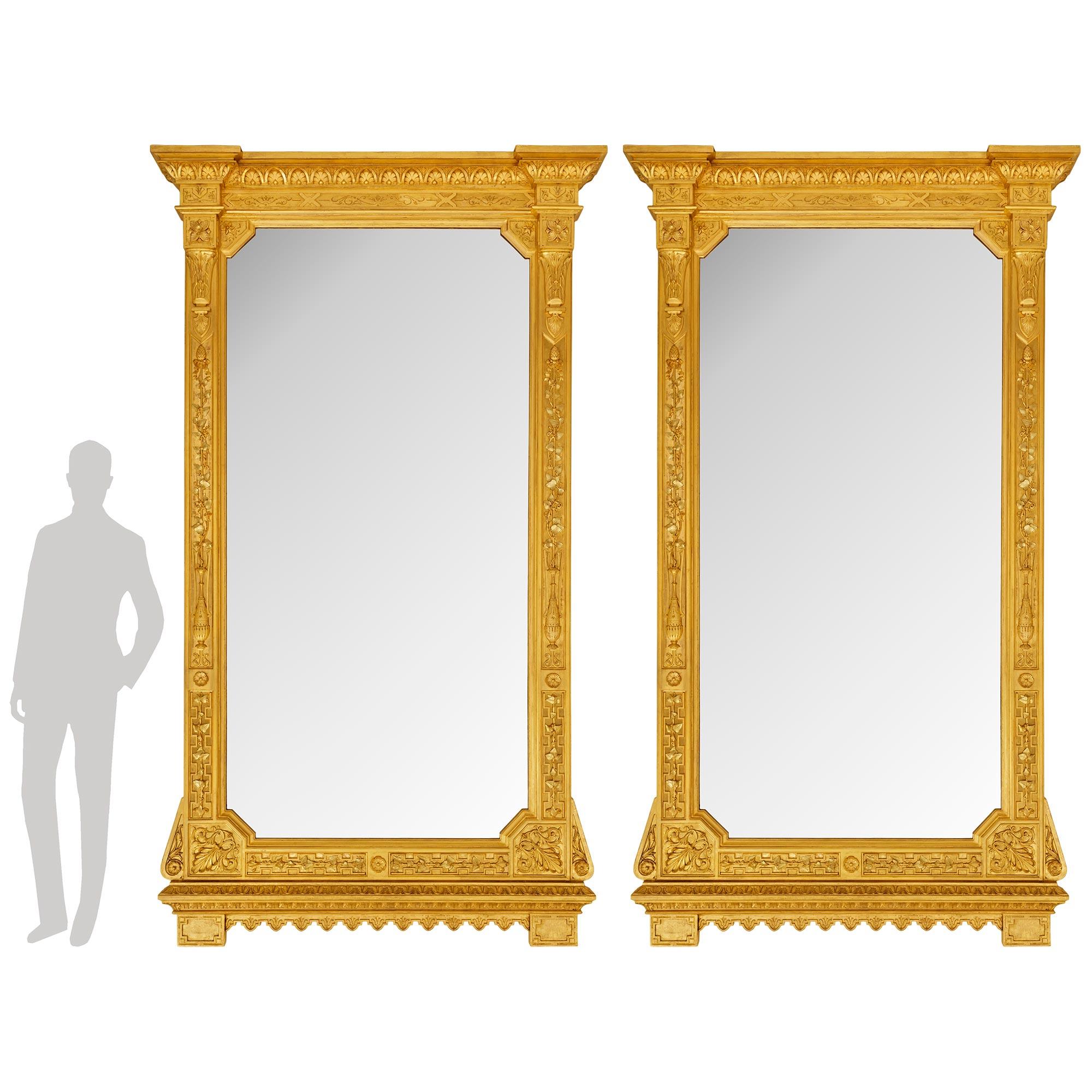 Ein beeindruckendes und monumentales Paar italienischer Spiegel aus Giltwood im Stil Louis XVI des 19. Jeder außergewöhnliche Spiegel wird von einem Paar rechteckiger Giltwood-Blöcke zwischen einer Reihe von umgekehrten maurischen Zinnen unter einer