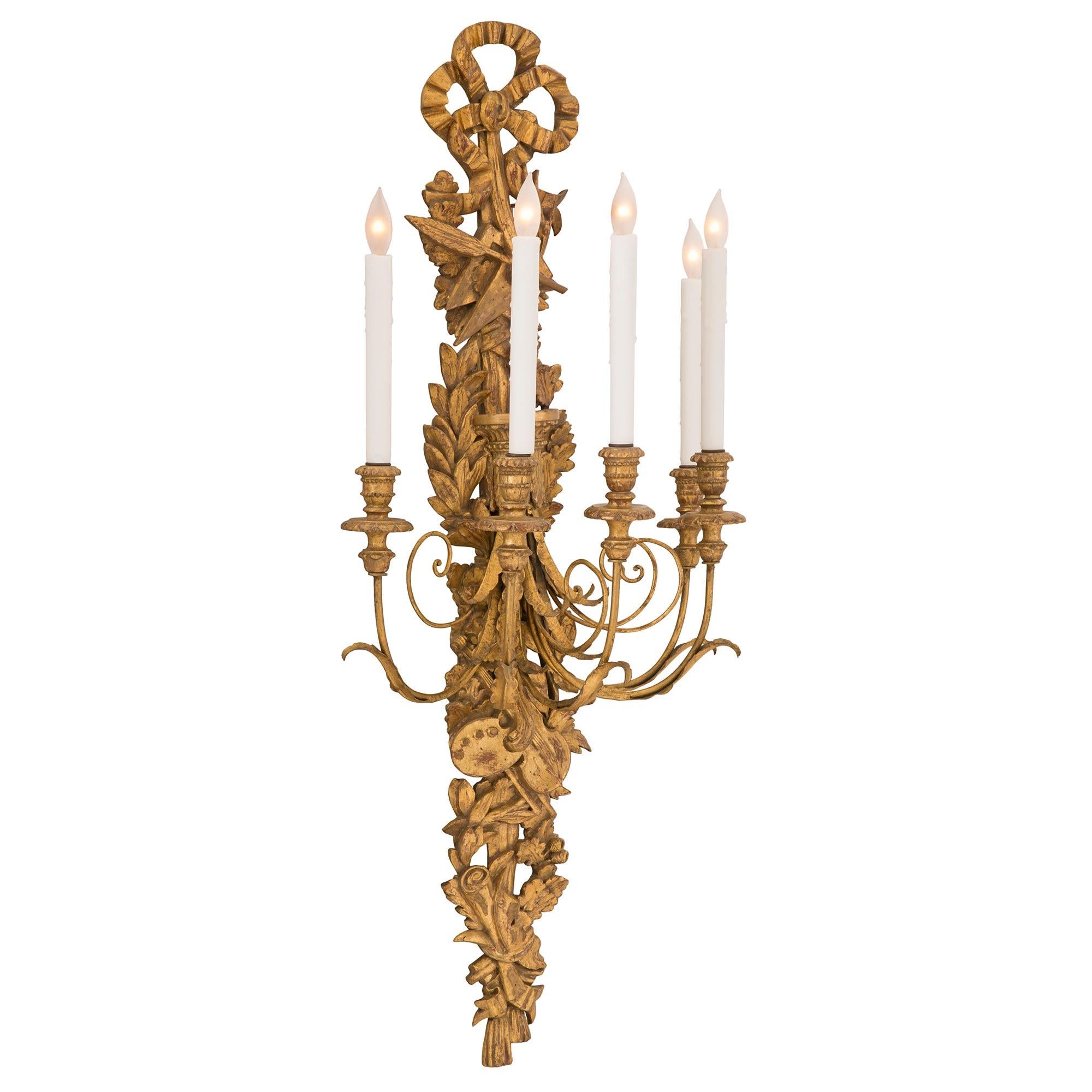 Une belle et très décorative paire d'appliques italiennes en bois doré de style Louis XVI du 19ème siècle. Chaque applique à cinq bras en bois doré présente une plaque arrière percée étonnamment détaillée avec de charmantes feuilles de chêne et des