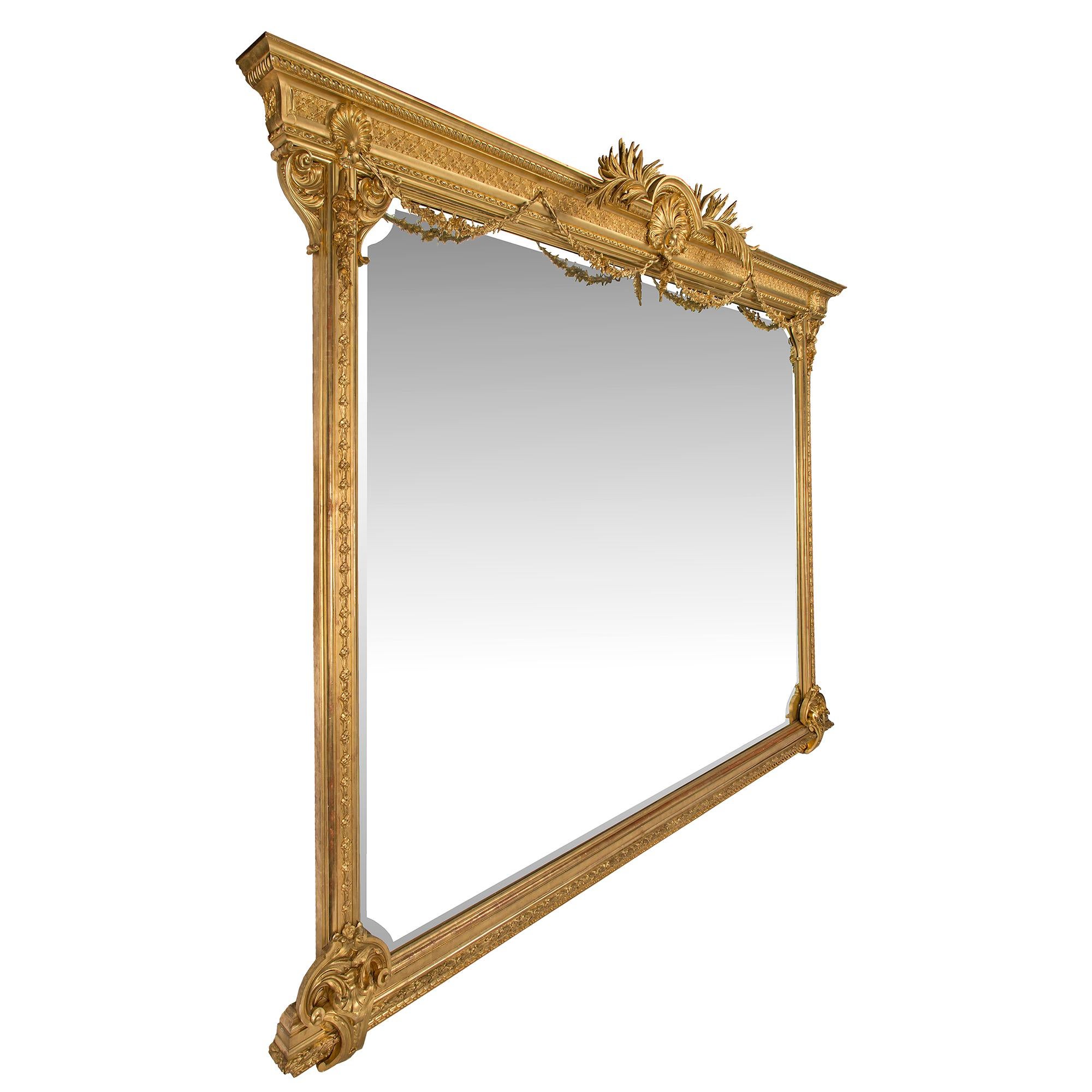 A monumental and extremely rare pair of Italian 19th century Louis XVI st. giltwood mirrors. The beveled mirrors are raised on a straight finely carved base accented with scrolls and acanthus leaves at each side. At the very impressive top crowns