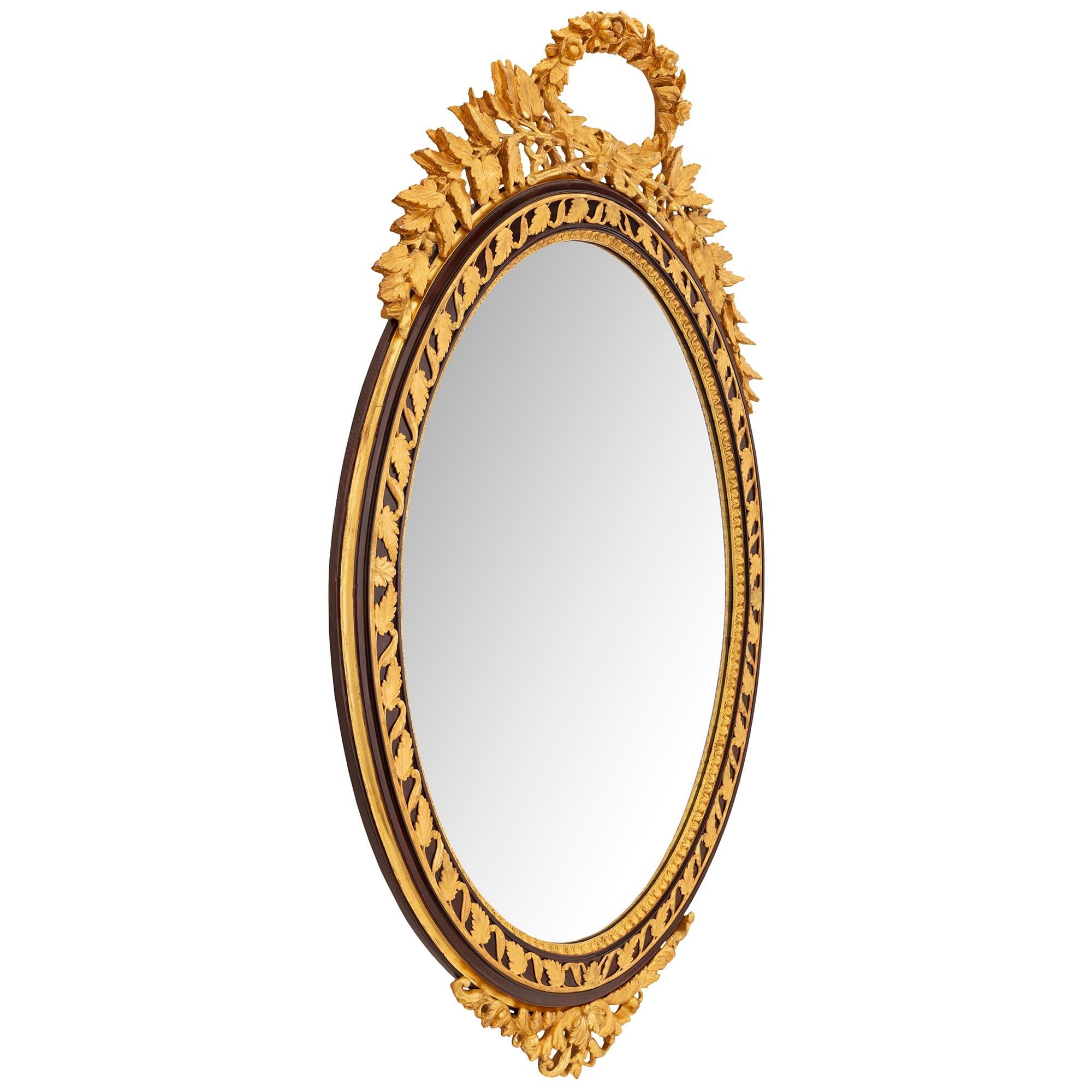 Une impressionnante et très élégante paire de miroirs italiens du 19ème siècle, de style Louis XVI, en bois polychrome et doré. Chaque miroir ovale a conservé ses plaques d'origine, dans un étonnant cadre polychrome moucheté avec une belle bande