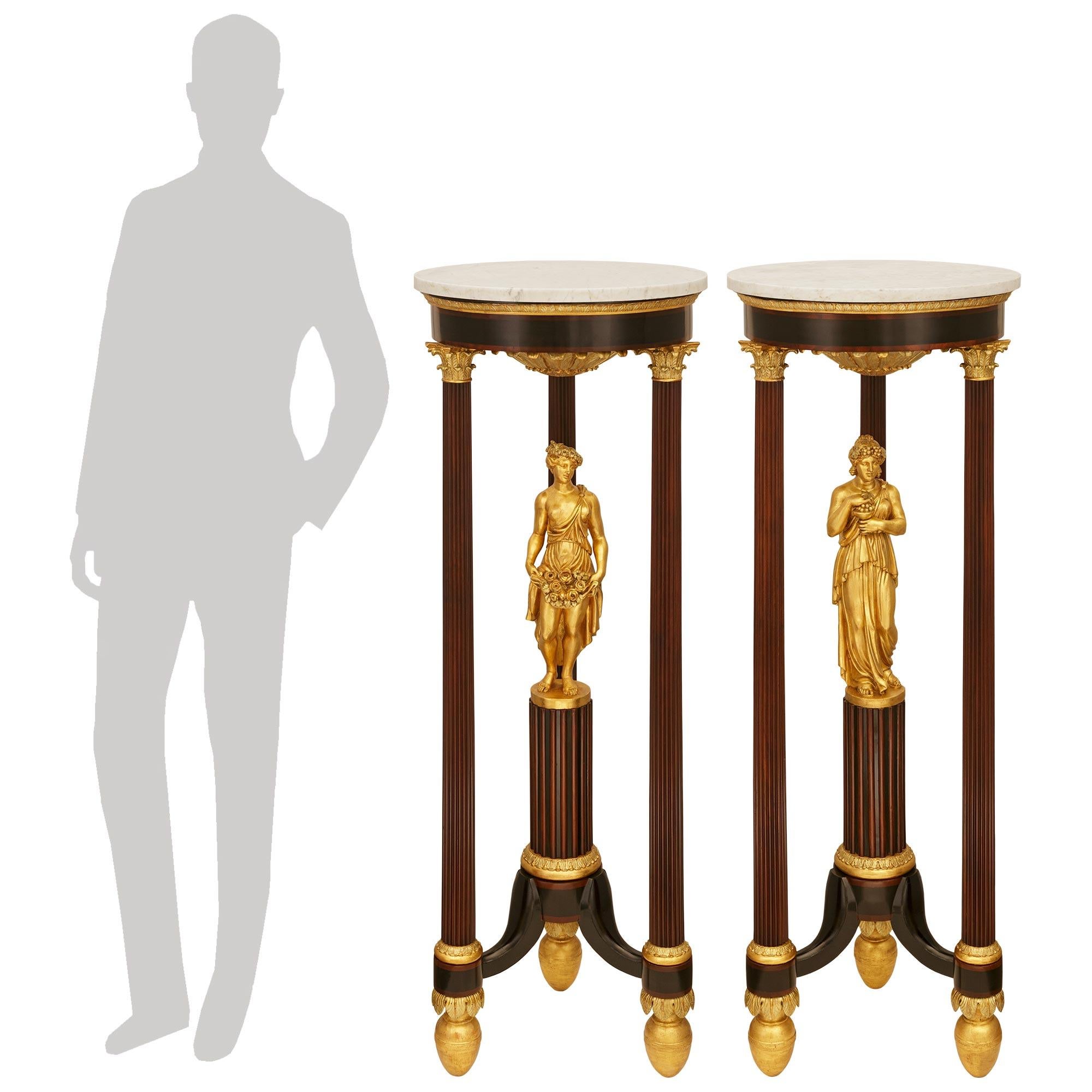 An impressive and most decorative pair of Italian early 19th century Neo-Classical st. Mahogany, Giltwood and white Carrara marble pedestals. Each most unique pedestal is raised by egg shaped Giltwood feet accented with draped palmettes. The legs