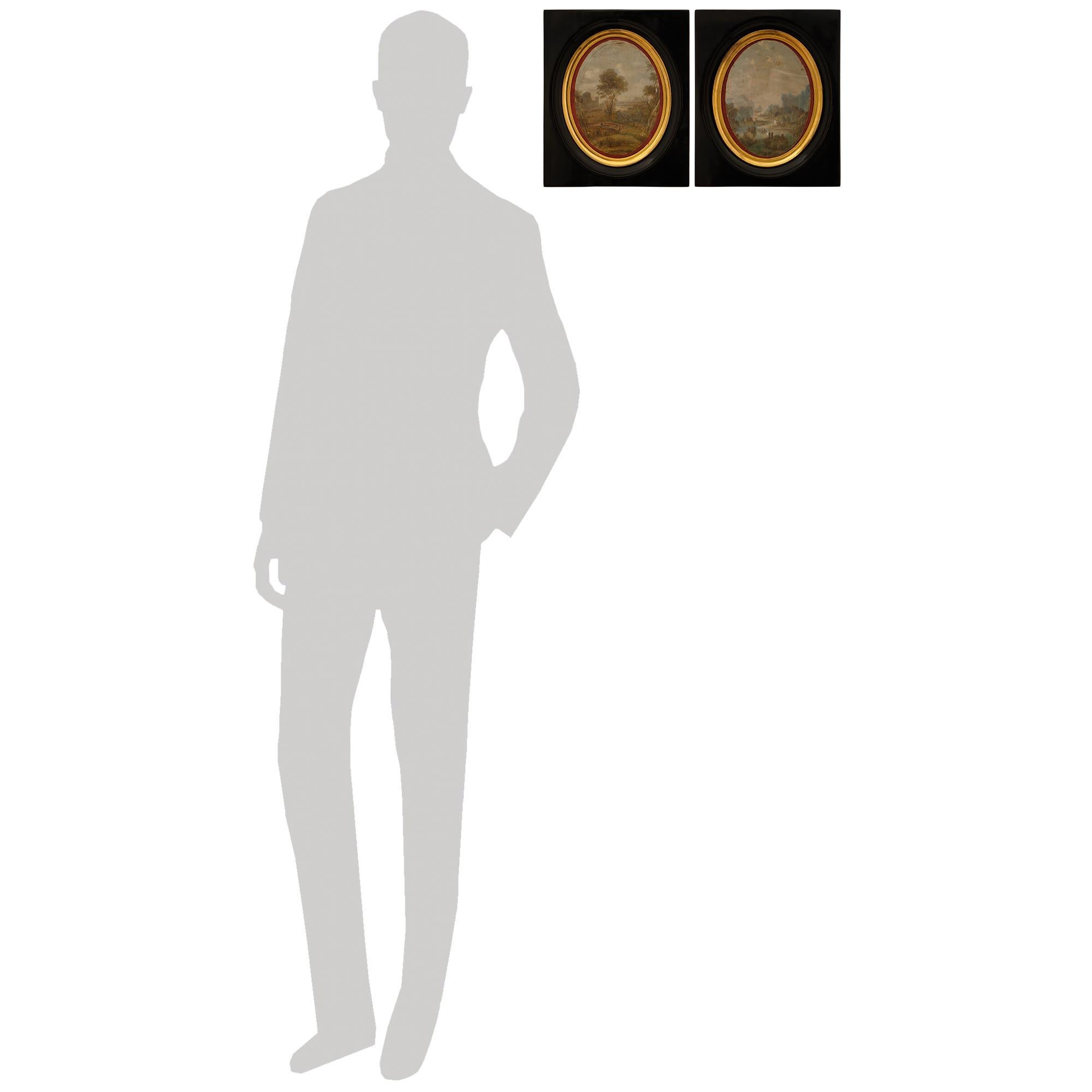 Une très belle paire de tableaux néo-classiques italiens du 19ème siècle. Tableaux en ébène, bois doré et soie. Chaque médaillon en soie peint à la main et merveilleusement décoratif est placé dans une bande intérieure ovale en bois doré tacheté,