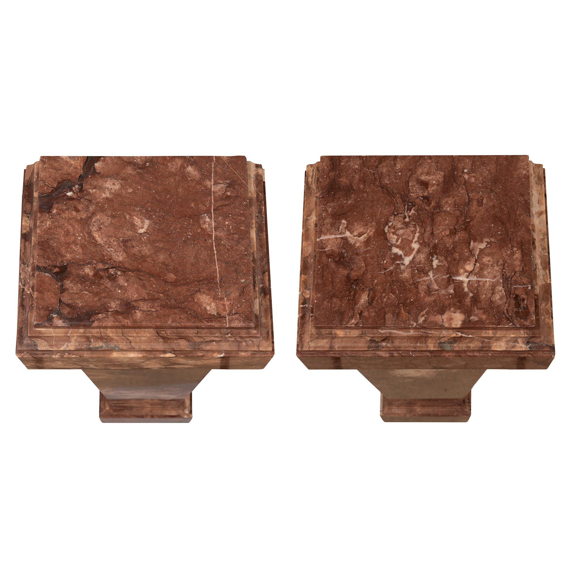 A beautiful pair of Italian 19th century neo-classical st. rouge marble pedestal columns. Each column is raised by a square base with a fine mottled border. The elegant lightly tapered square central supports display decorative cut corners while the