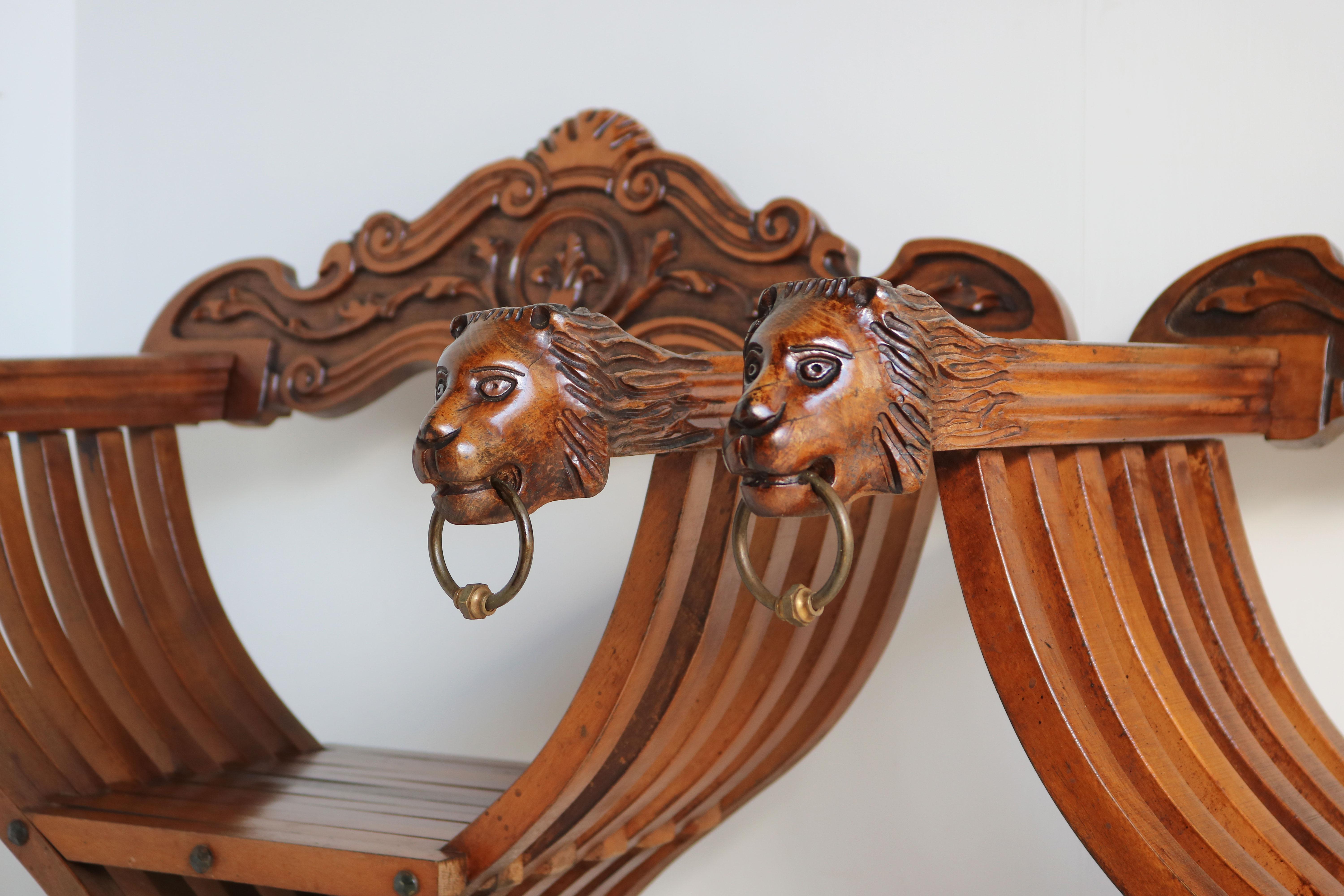 Impressive & fully original pair of Florentine Renaissance Savonarola chairs in carved birch. Armrests ending with two amazing hand-carved lion heads both lions holding brass rings. The lion heads where used to display the power/might of the one who