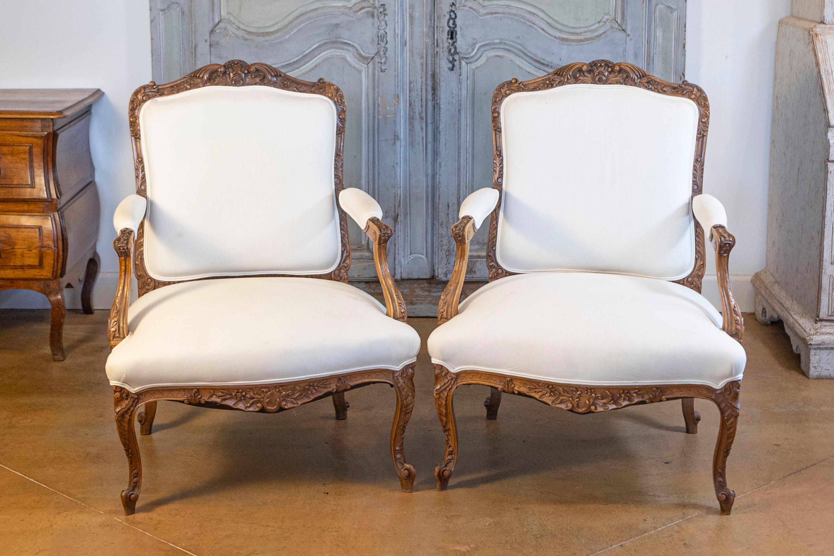 Coppia di poltrone in noce in stile rococò italiano del XIX secolo, con gonne intagliate, gambe a cabriola e imbottitura. Nata in Italia nel XIX secolo, questa coppia di poltrone in stile rococò è caratterizzata da uno schienale leggermente