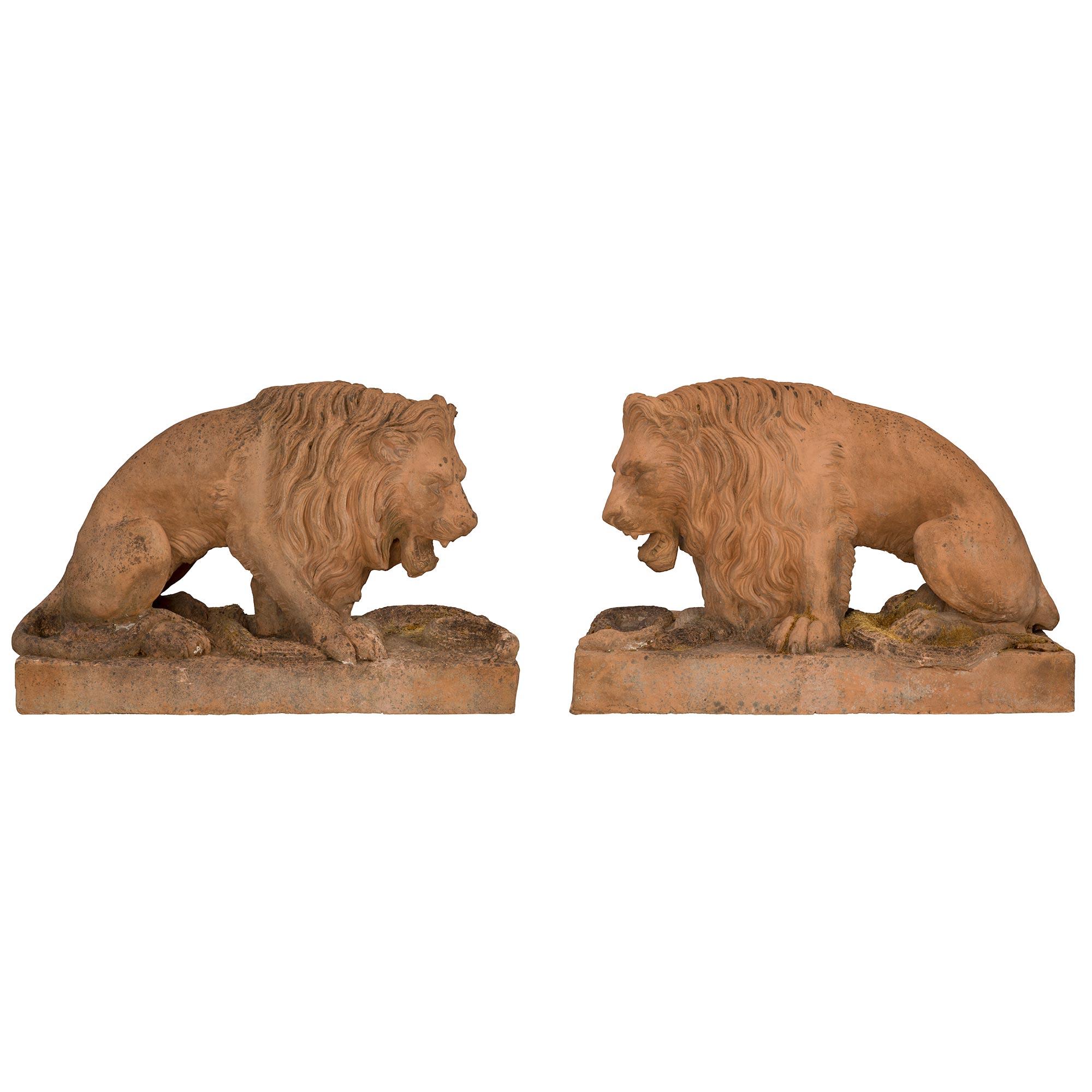 A most impressive true pair of Italian 19th century terra cotta statues of lions, circa 1850. Each statue is raised by a rectangular base with a beautiful ground like design and a serpent that the lion has trapped under his paw. Each richly detailed