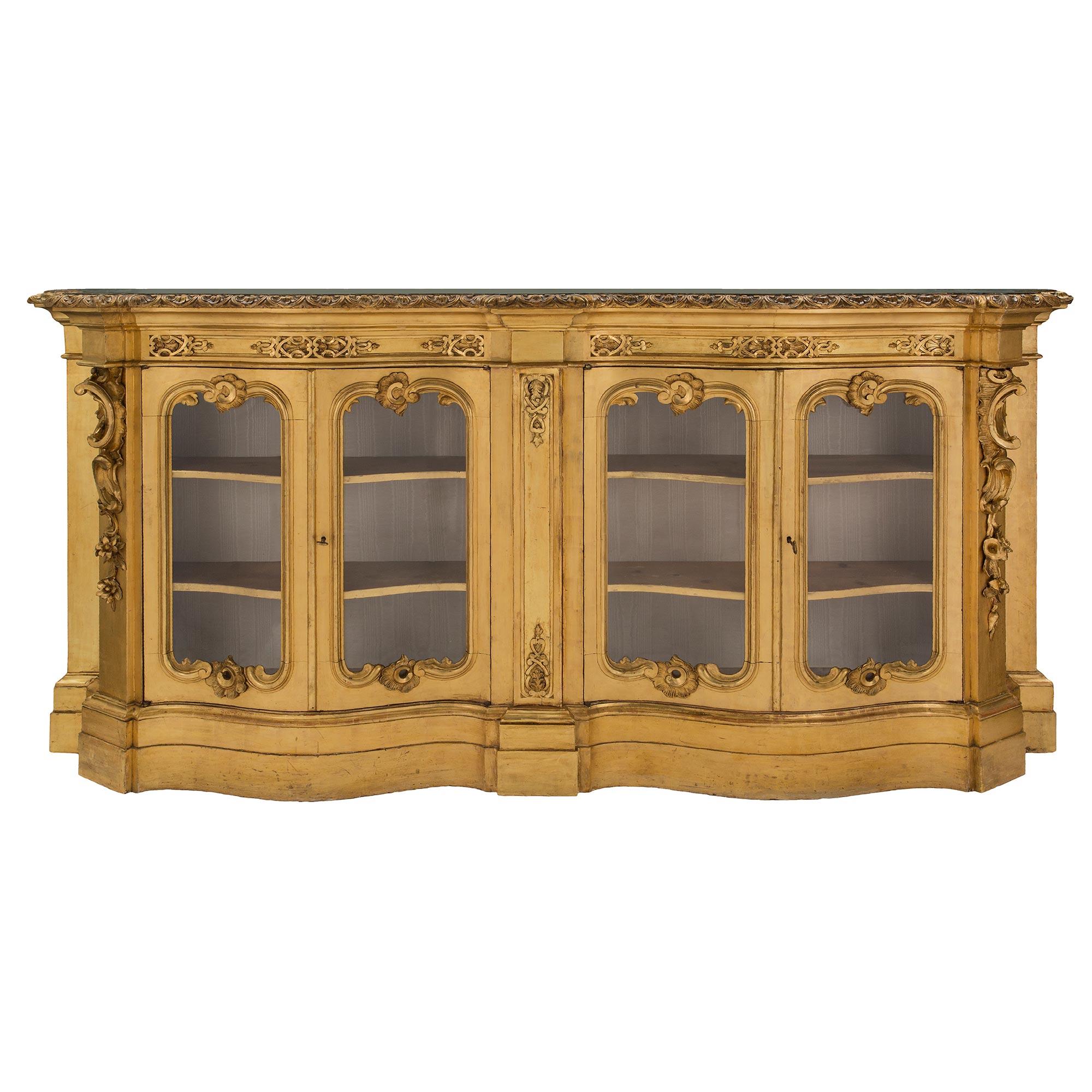 A stunning and large scale complimentary pair of Italian 19th century Venetian style giltwood vitrines. The most impressive and uniquely shallow vitrines are each raised by a bombée and scalloped shaped base with a decorative stepped design. At the