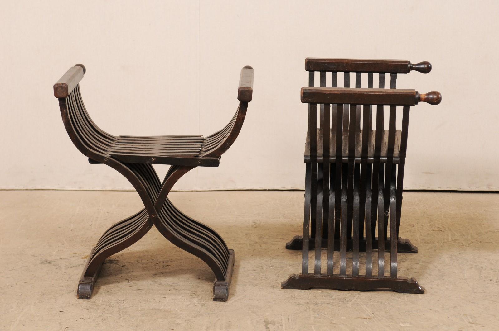 An Italian pair of walnut wood Dante style chairs from the early 20th century. This pair of antique chairs from Italy have the signature Savonarola or Dante style frames, whereas their X-shaped bodies are developed with criss-crossed legs, which