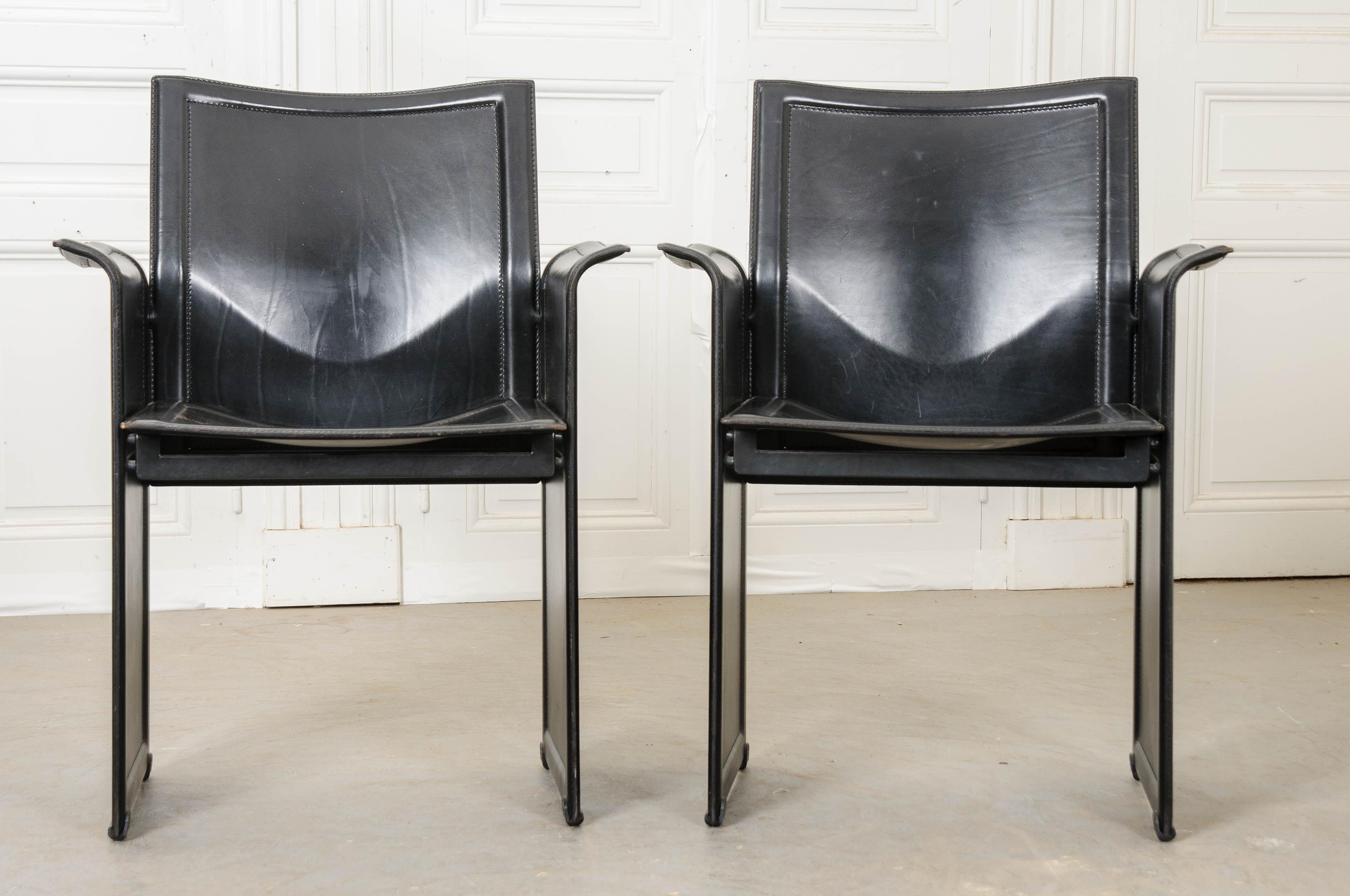 This stylish pair of black leather armchairs was made in Italy by Tito Agnoli for Matteo Grassi, circa 1970. The chairs’ design has a Mid-Century Modern influence with clean lines and a unibody form. Made totally of leather with an obscured and