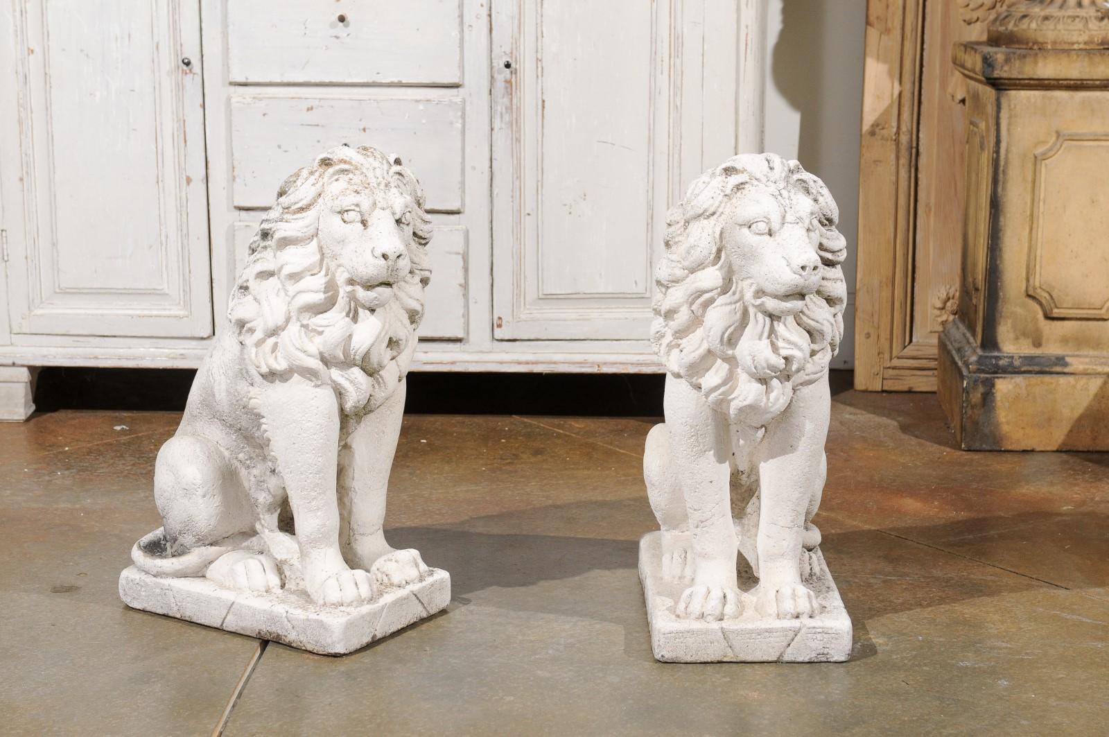 A pair of Italian reconstituted stone seated lions sculptures from the 20th century with great mane. Created in Italy during the 20th century, this pair of sculptures, made of reconstituted stone, features two lions seated in a calm pose. Our eyes