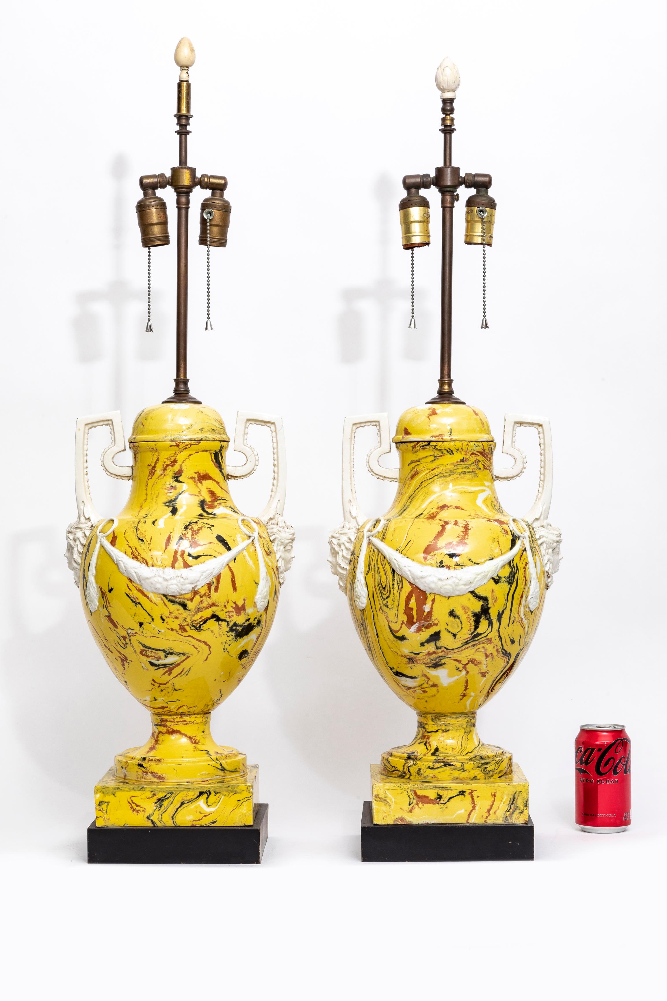 A Magnificent Pair of Italian Agateware Porcelain Lamps with Medusa Masks, Wreaths, and Handles.  The lamps are fashioned in the neoclassical style and feature a brightly-contrasted yellow and brown marbling. Atop the solid dark brown plinths stand