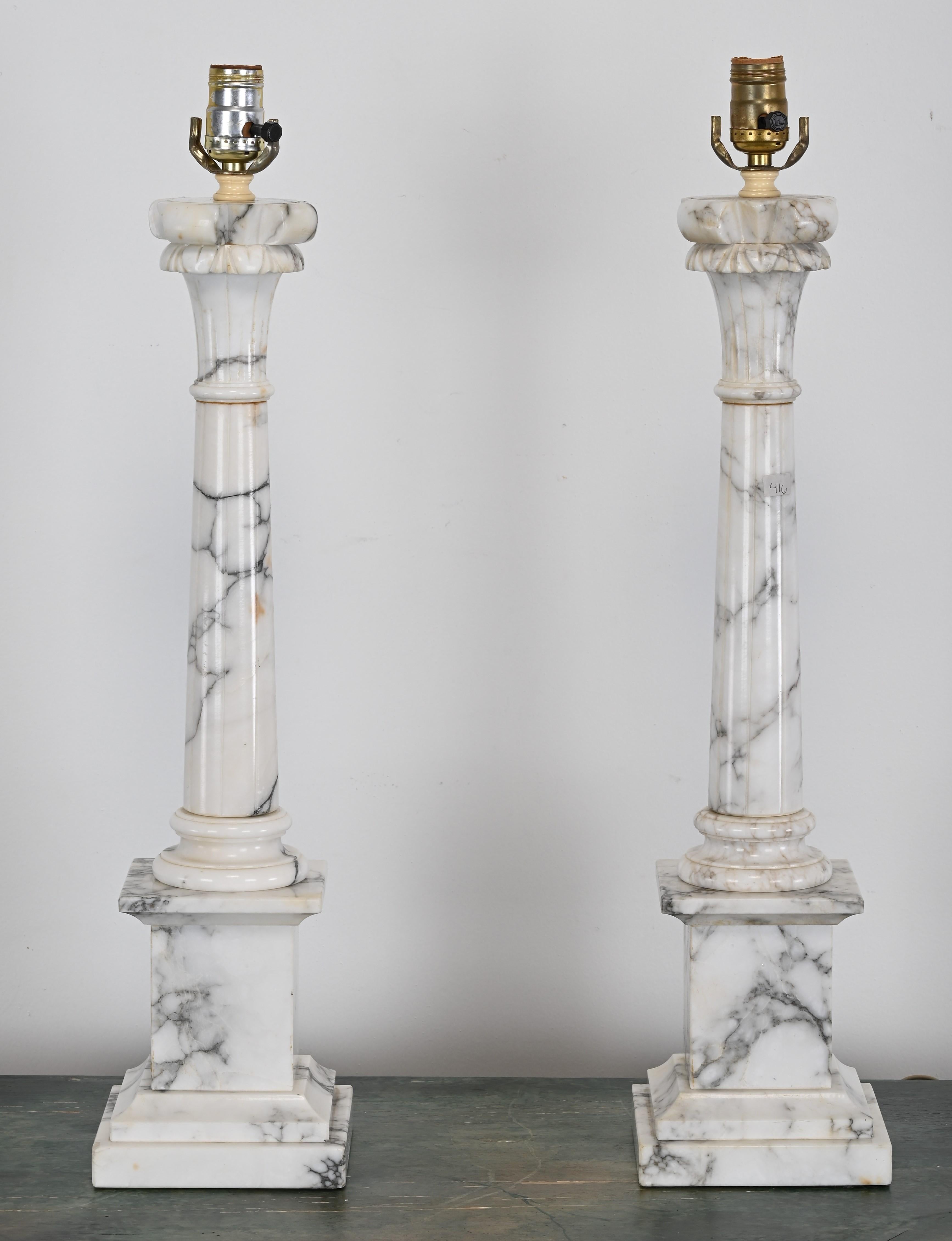 A neoclassical pair of Alabaster lamps in the manner of Corinthian Column. This pair would look great in any antique or classical interior. The electrical wire has not been checked but new wiring is recommended. There is one chip but not easy to see