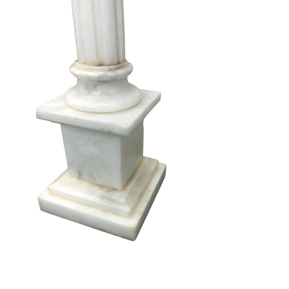 These stunning and elegant lamps are made of high-quality alabaster, with a simple columnar design that is decorated with delicate reeded grooves capped with an ionic capital. The columns sit atop a square plinth base. They are newly wired with a