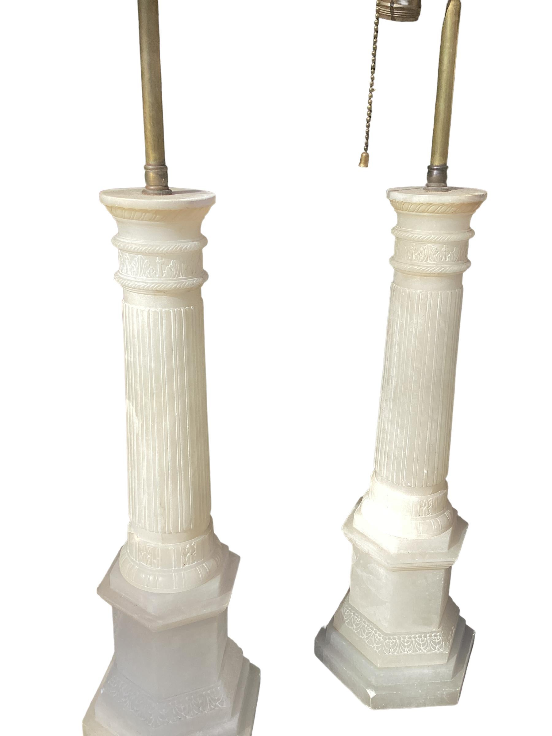 Paar italienische Alabaster-Säulenlampen. Jeweils mit einer geriffelten Säule mit runden Kapitellen, die auf einem sechseckigen Sockel steht. Die Oberseite des Doppelcluster-Sockels ist mit einem verstellbaren Rohr versehen, mit dem der Schirm um