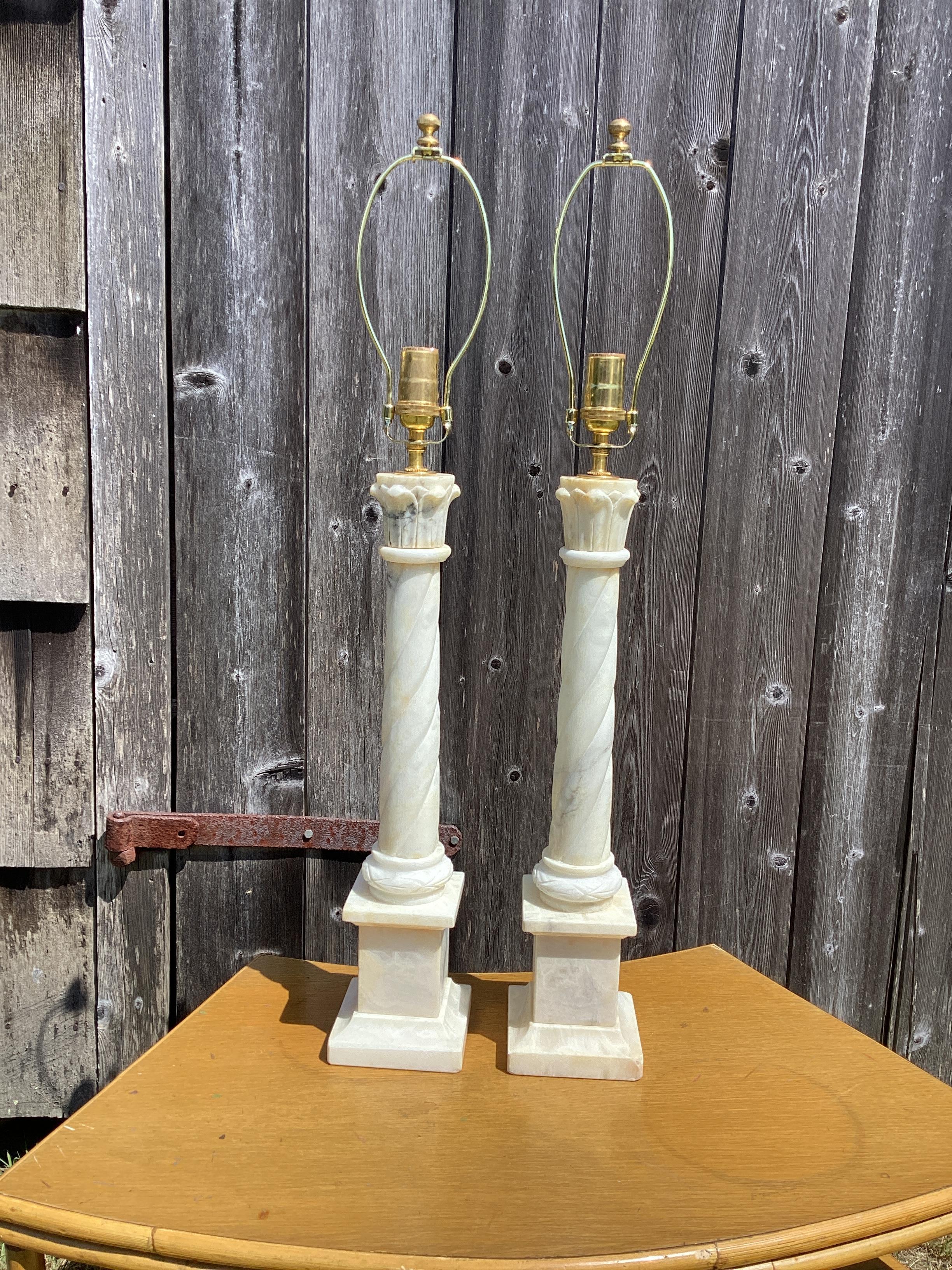 Pair of Italian Alabaster Column Lamps. Spiral columns with  carved capitals sits atop a square plinth base. Lamps have been professionally wired with new 3-way sockets. The lamps measure 19