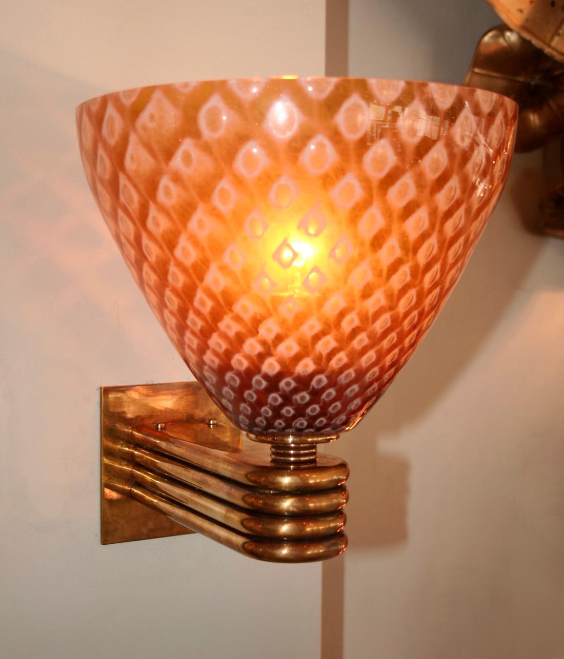 Exotic and moody wall lights with Murano glass conical shades in a caramel pattern held by fluted brass arms.

Can be purchased individually.