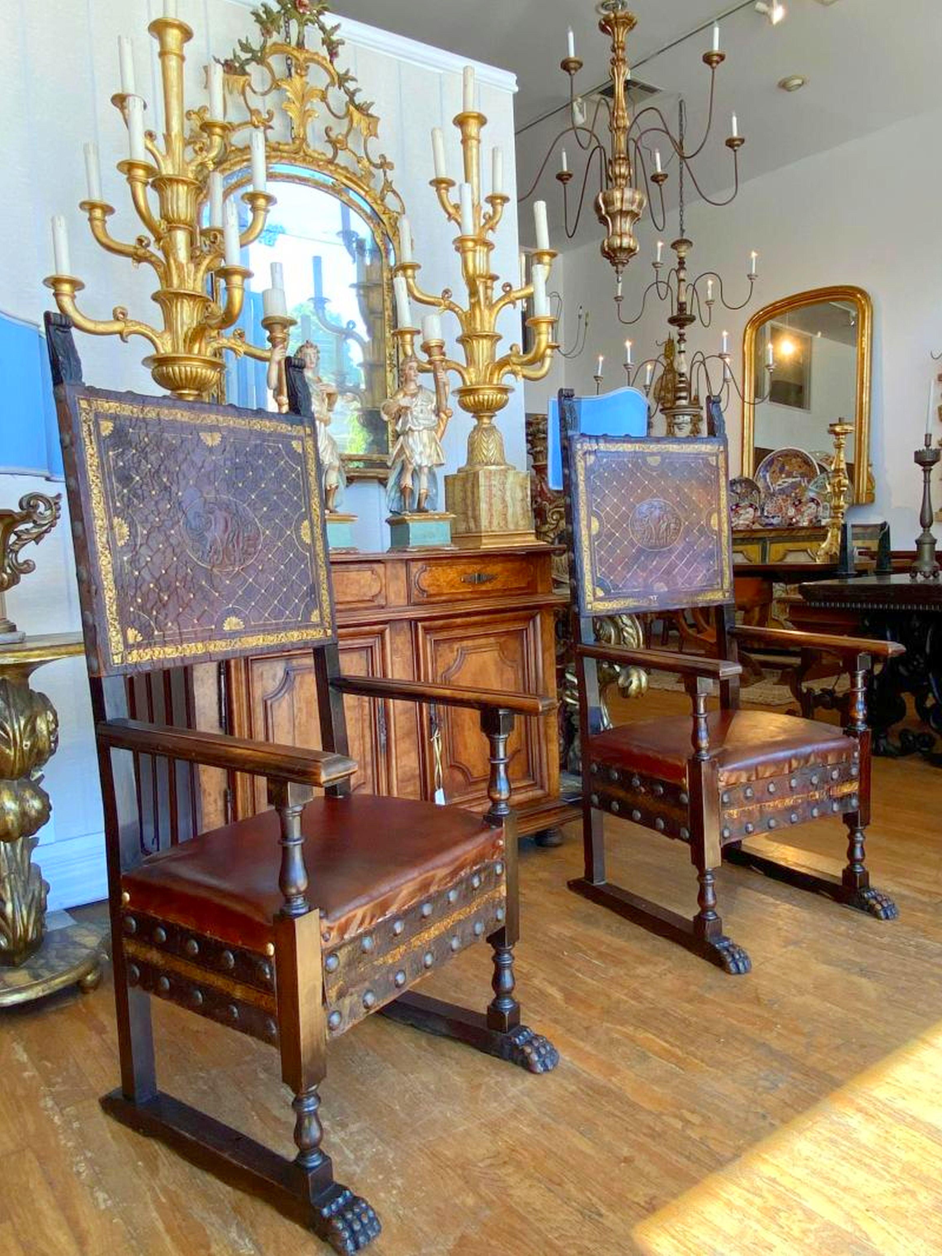Tooled leather paneled backs with scroll finals, having straight arm supports above a leather and brass trim seat raised on square legs joined a geometric decorated panel and stretchers.