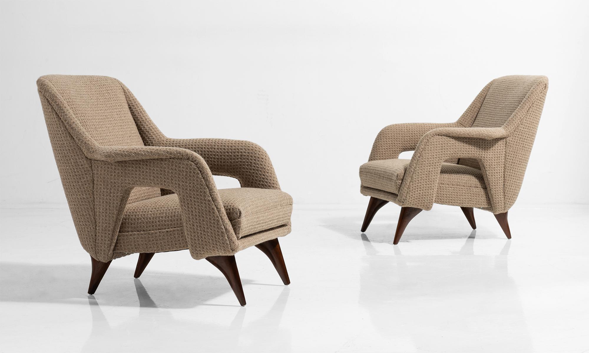 Modern armchairs with wool upholstery tapered wooden legs.

 