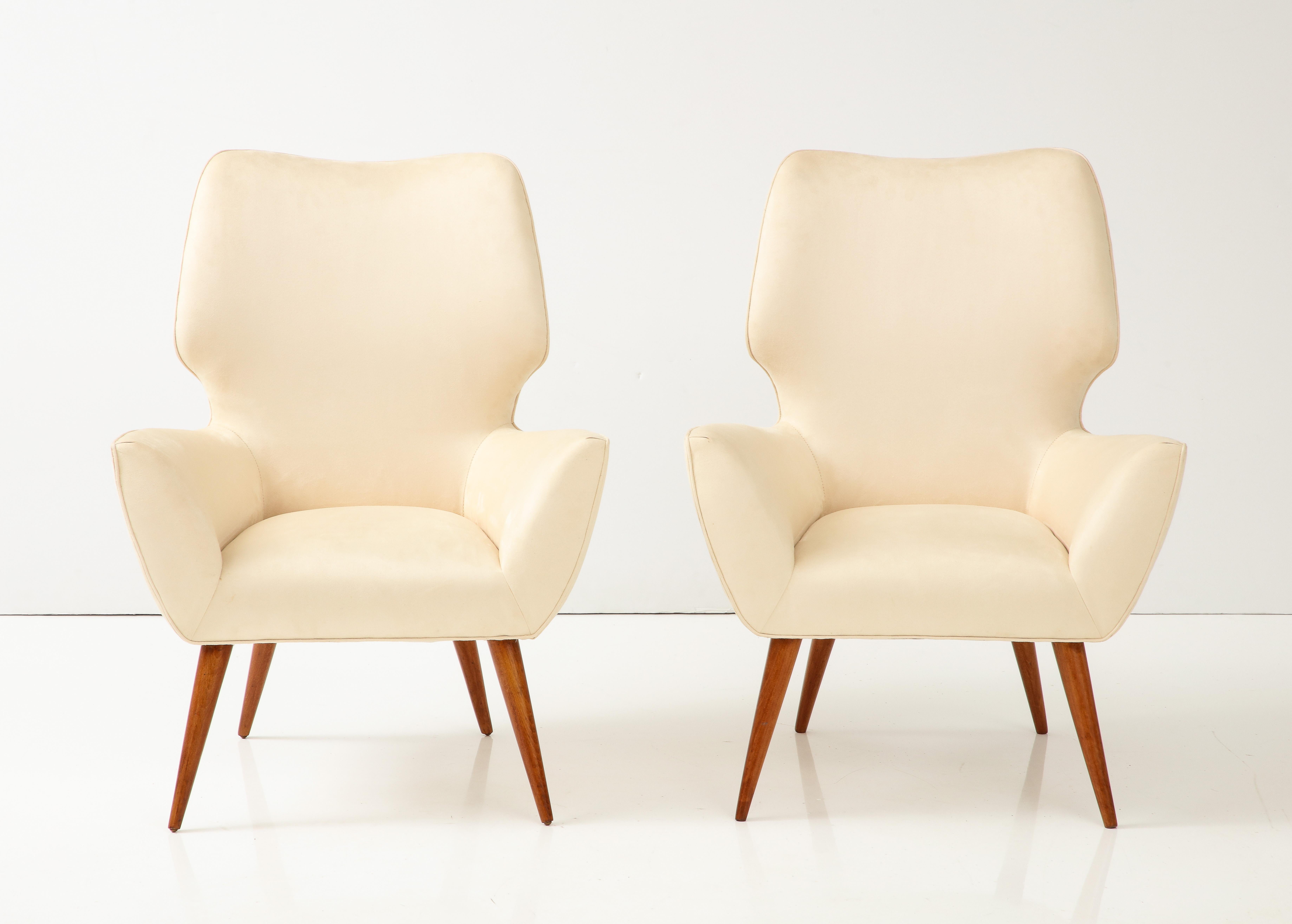 Pair of Italian armchairs with highly sculptural backrests and sides supported on elegantly tapered wood legs.  Newly refinished and upholstered in a creamy faux suede. 
Italy, circa 1940's 
Size: 34 1/4