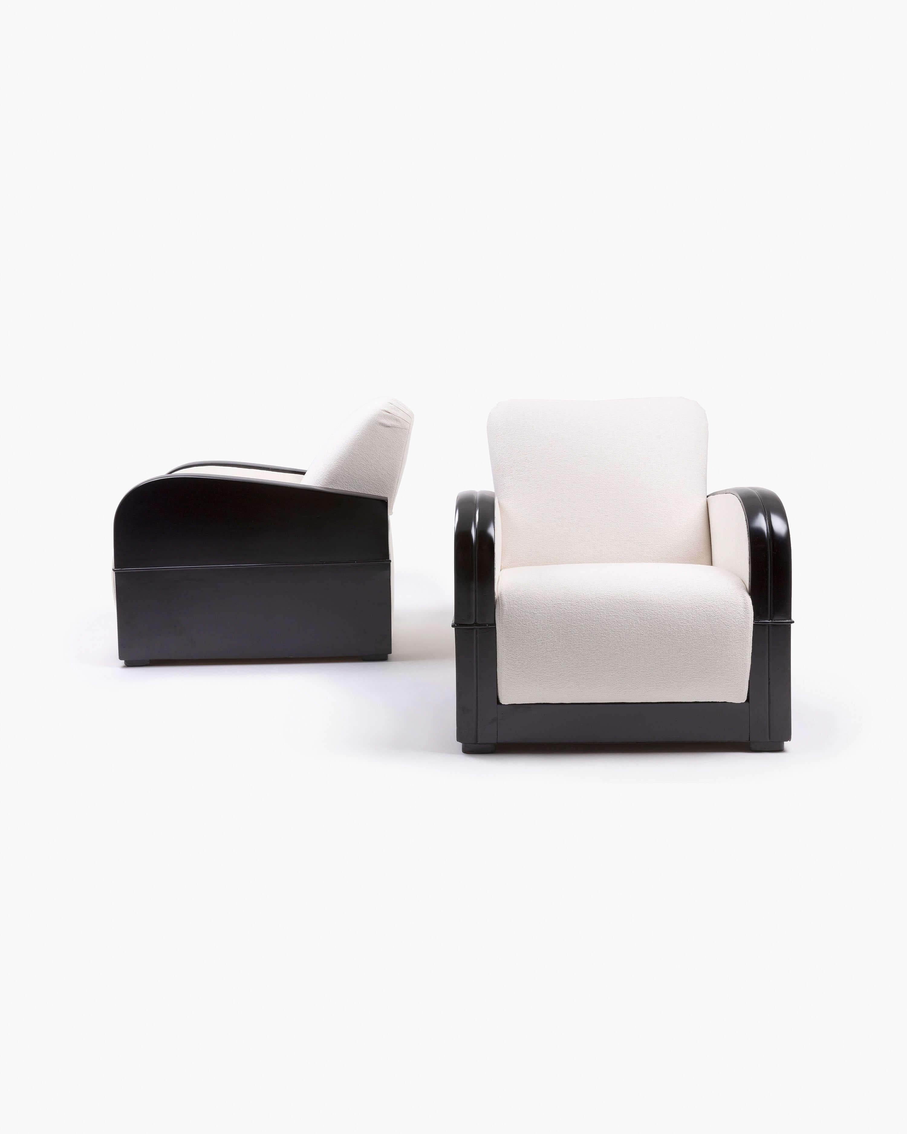 This pair of black lacquered armchairs features plush white bouclé cushioning. High-gloss features are softened slightly by the tufted upholstery to create a luxurious yet cozy set of club chairs–a perfect feature for any thoughtfully curated living