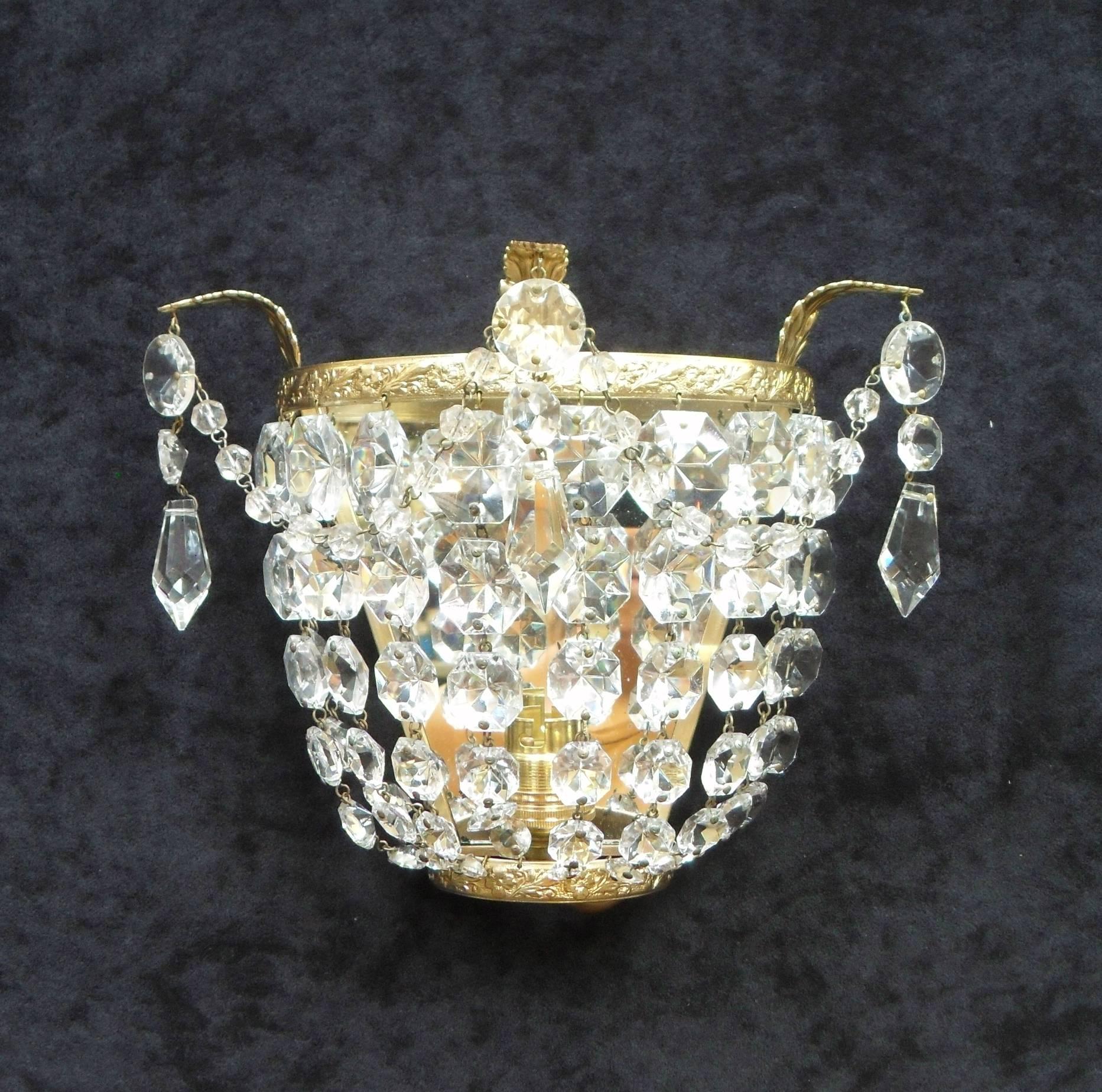 An extremely good quality pair of Italian Art Deco basket shaped wall lights with graduating diamond shaped cut crystal glass, glass beaded swags and hanging pendants. The lights have decorative floral leaf scrolling brass frames with hanging leaves