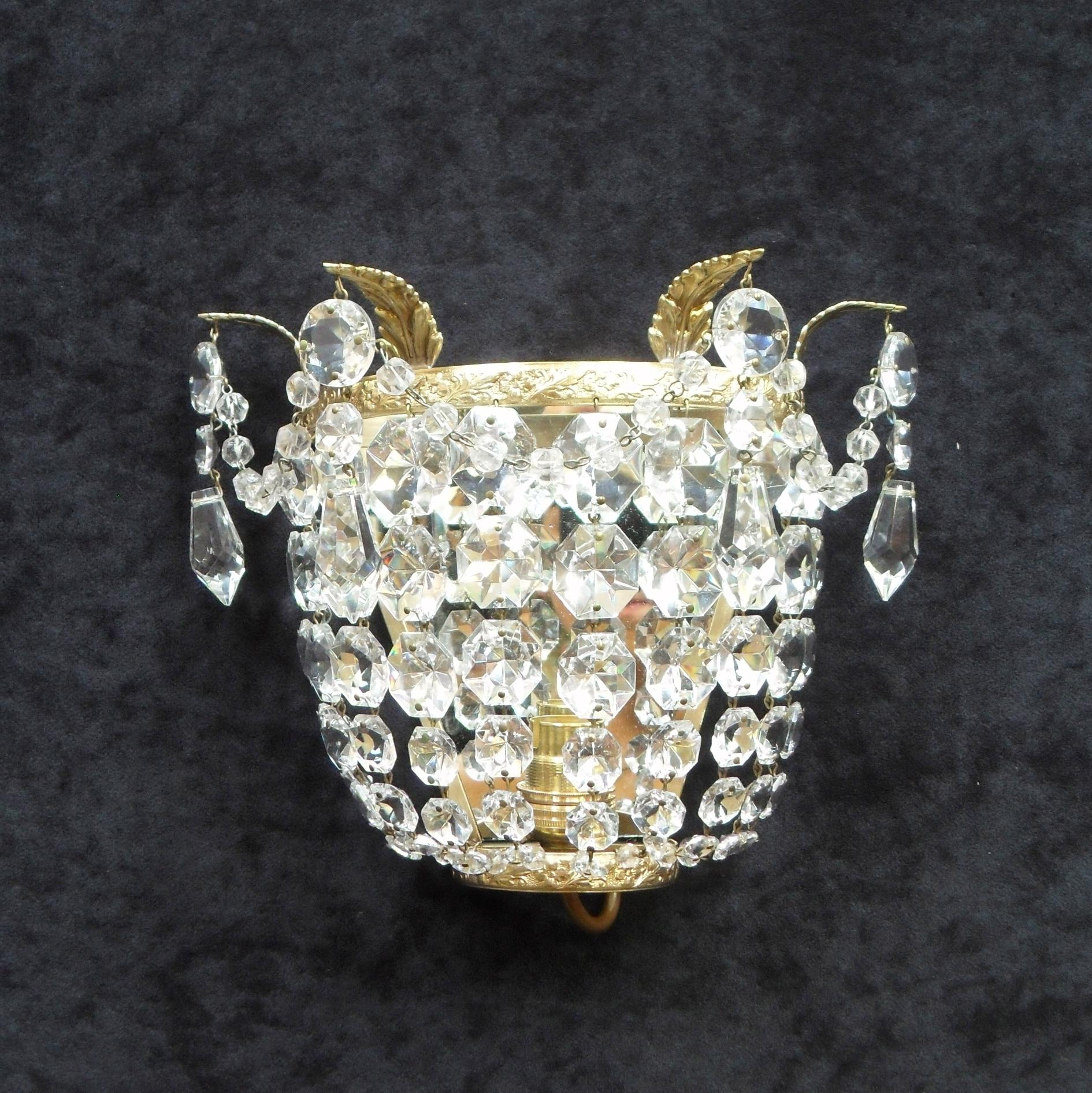 An extremely good quality pair of Italian Art Deco basket shaped wall lights with graduating diamond shaped cut crystal glass, glass beaded swags and hanging pendants. The lights have decorative floral leaf scrolling brass frames with four hanging