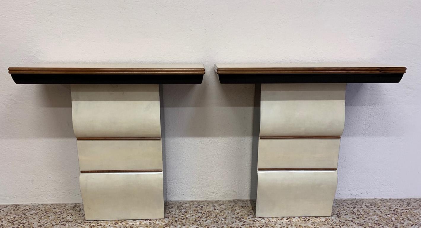 This pair of consoles was produced in Italy in the 1940s.
The front part of the base and top are covered with parchment leather with walnut profiles.
The side of the base is black lacquered.