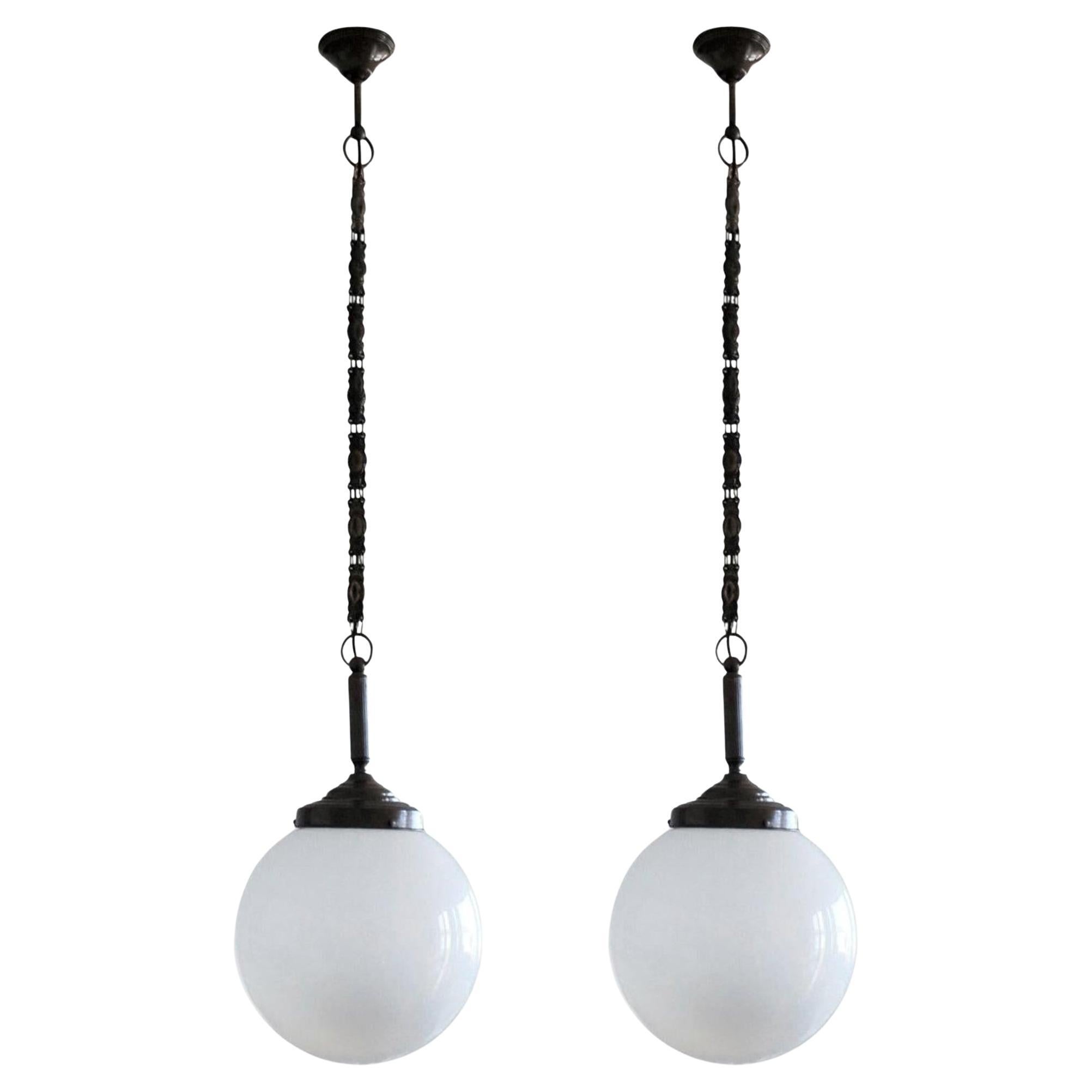 Pair of hand blown Opaline glass ball pendants with burnished brass mounts, chain and canopy, Italy, 1930-1939.
One porcelain E27 light socket for a large sized bulb up to 100W.
Measures: Diameter 12