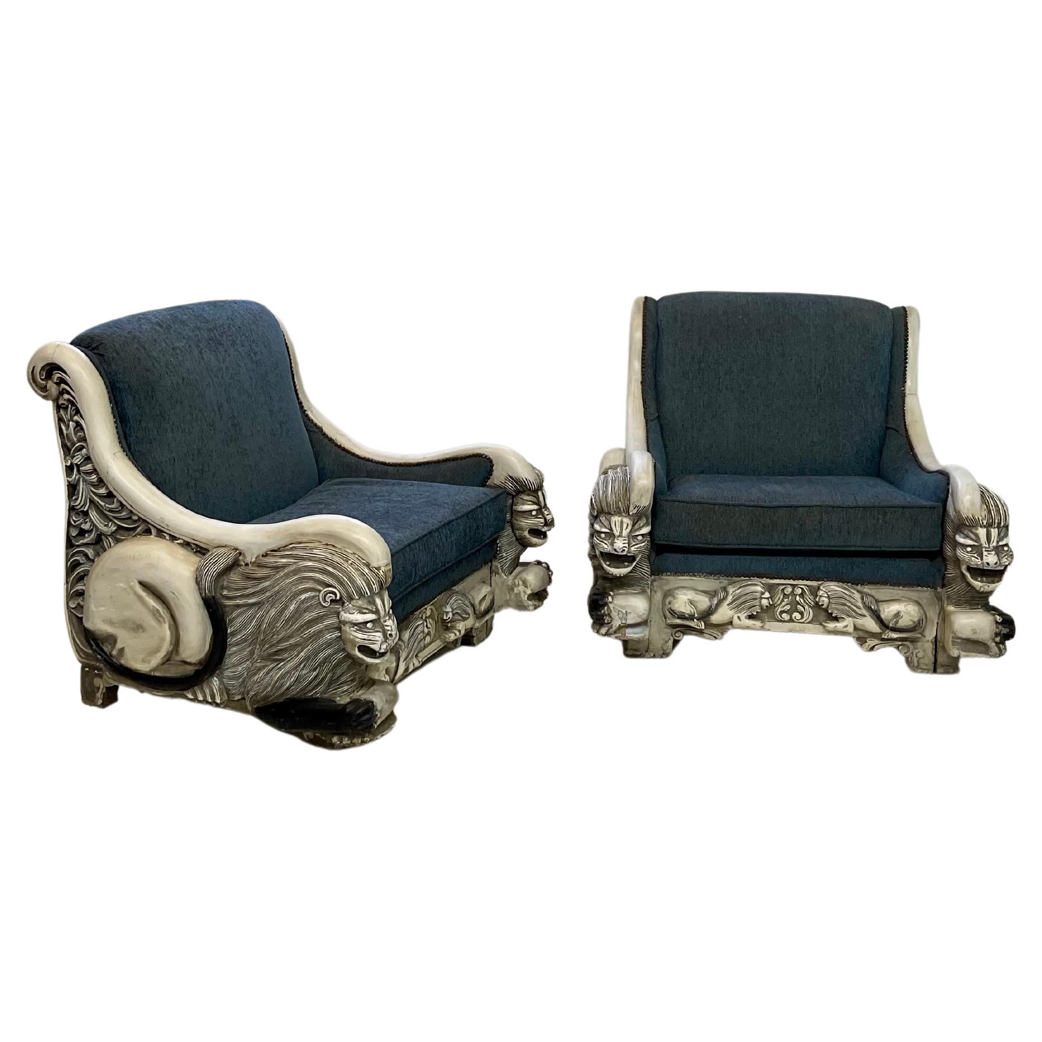 Early 20th Century pair of oversized Italian Art Deco lounge chairs with intricately detailed reclined lion carvings on each arm and in miniature along the front center apron. The chair frames are in a black and white painted finish and comfortably