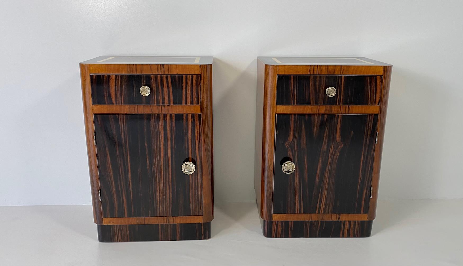 This Elegant pair of Art Deco nightstands was produced in Italy in the 1930s. 

The body is made of Walnut covered solid wood, while the drawer, the door and the base are in Macassar. On the top there is an elegant decoration made of gold leaf. On