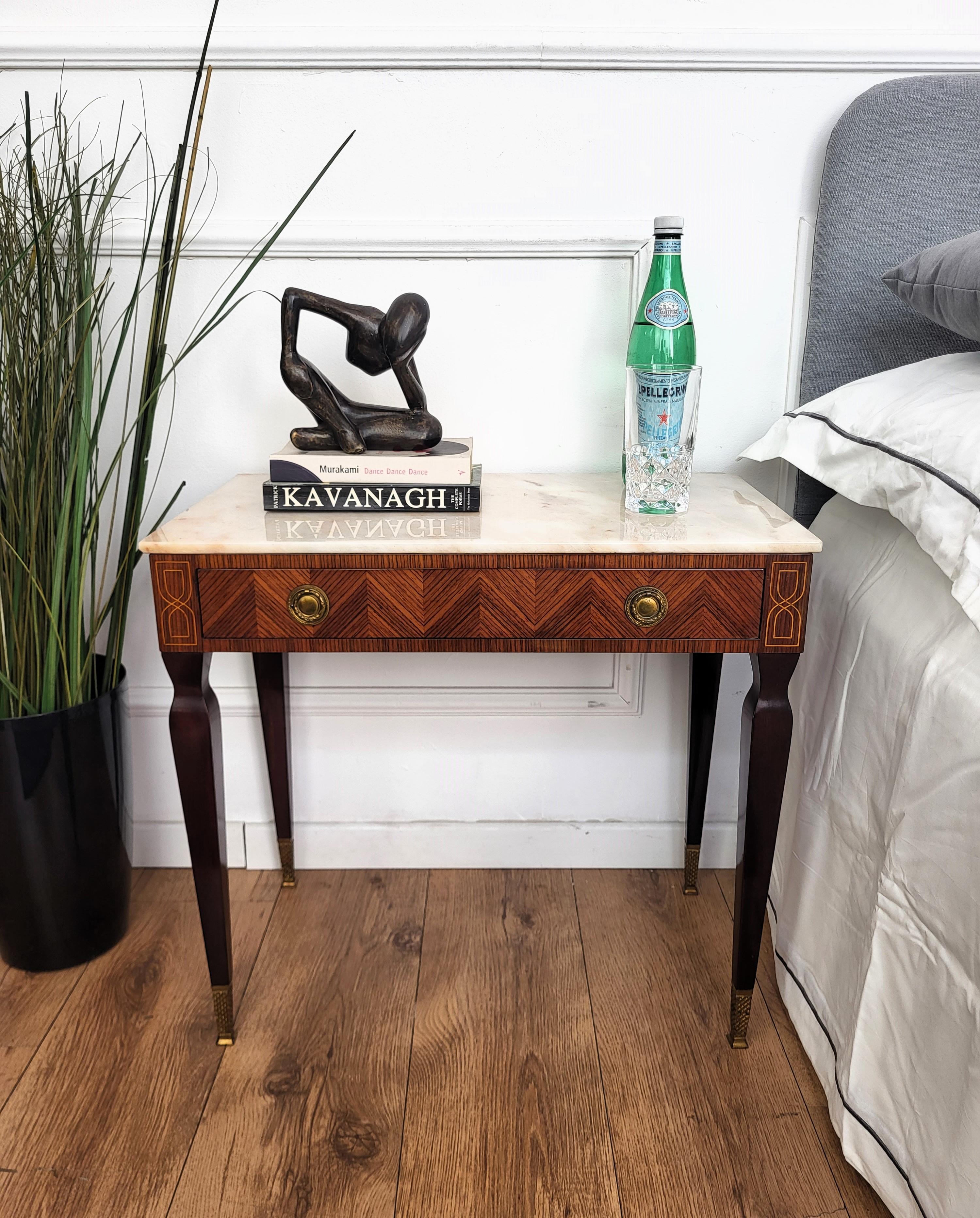 Very elegant and refined Italian 1950s Art Deco Mid-Century Modern pair of night stands bed side tables with greatly carved marquetry detail decorated wooden structure, one front drawer and white marble top with brass details and black squared