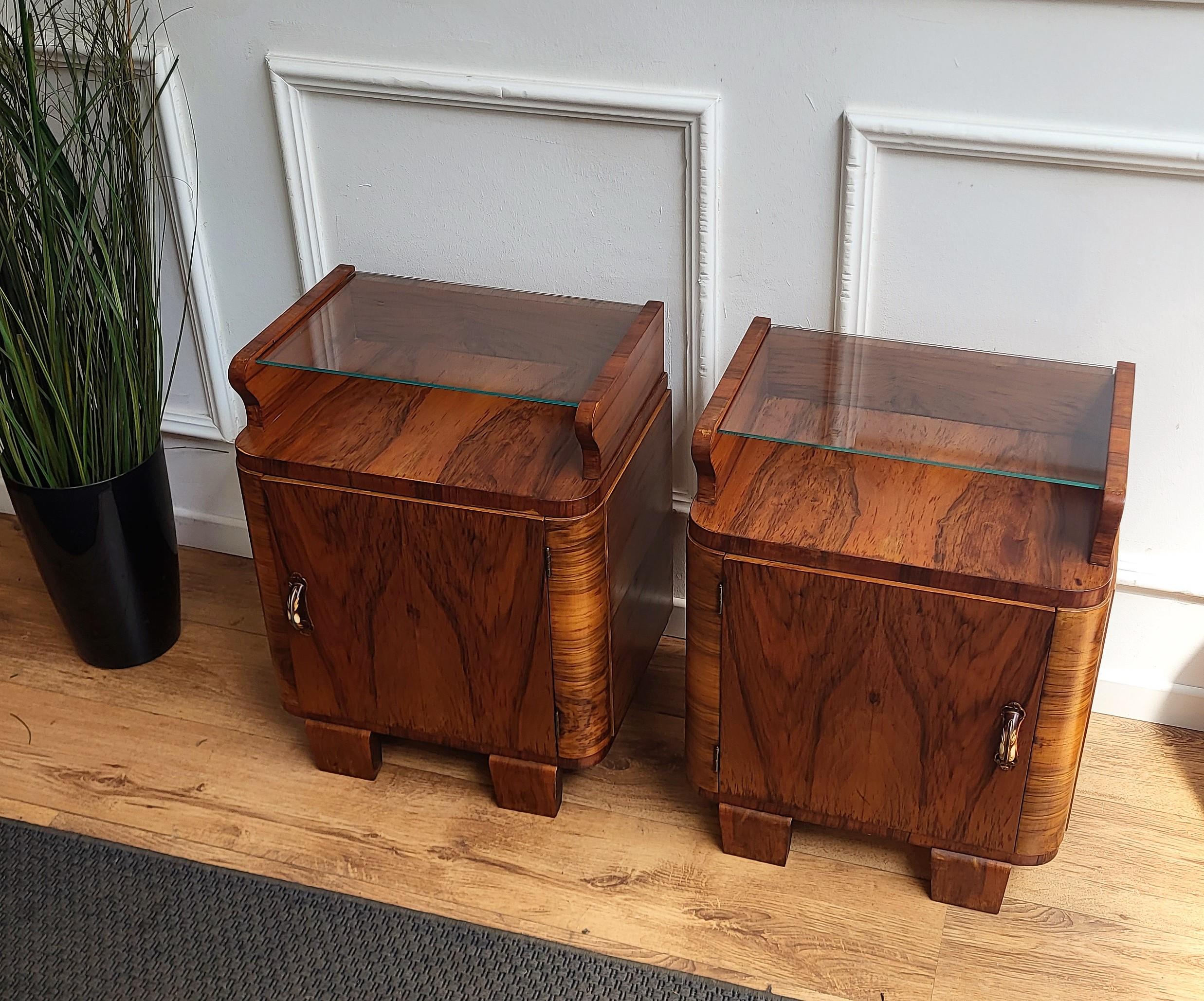 Very elegant and refined pair of Italian 1940s Art Deco bedside tables with great design shape and decors in veneer burl walnut briar wood, front door and top glass shelf. This night stands make a great look in any style bedroom, as a complementary
