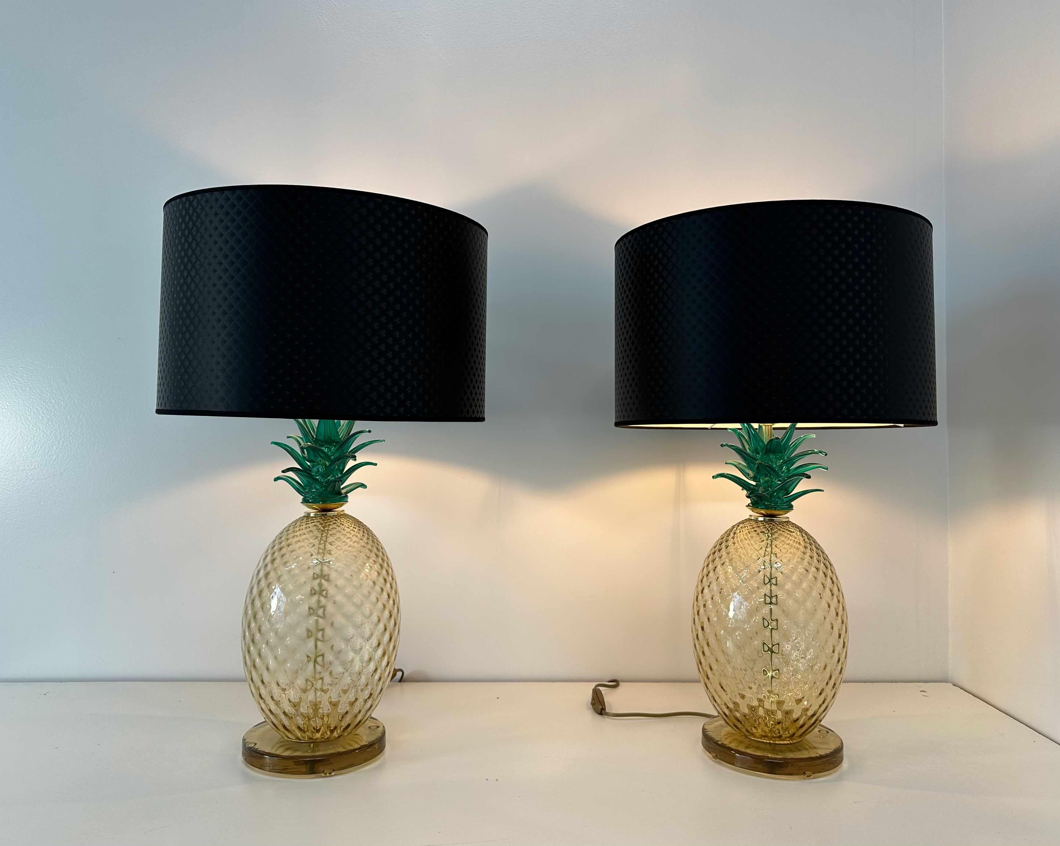 This pair of particular Art Deco style table lamps was produced in Murano, Italy in the 2000s. 
The central body is in pineapple shaped Murano glass, handcrafted by glass artists and the lampshade is in a dark grey pattern with a black profile. 
