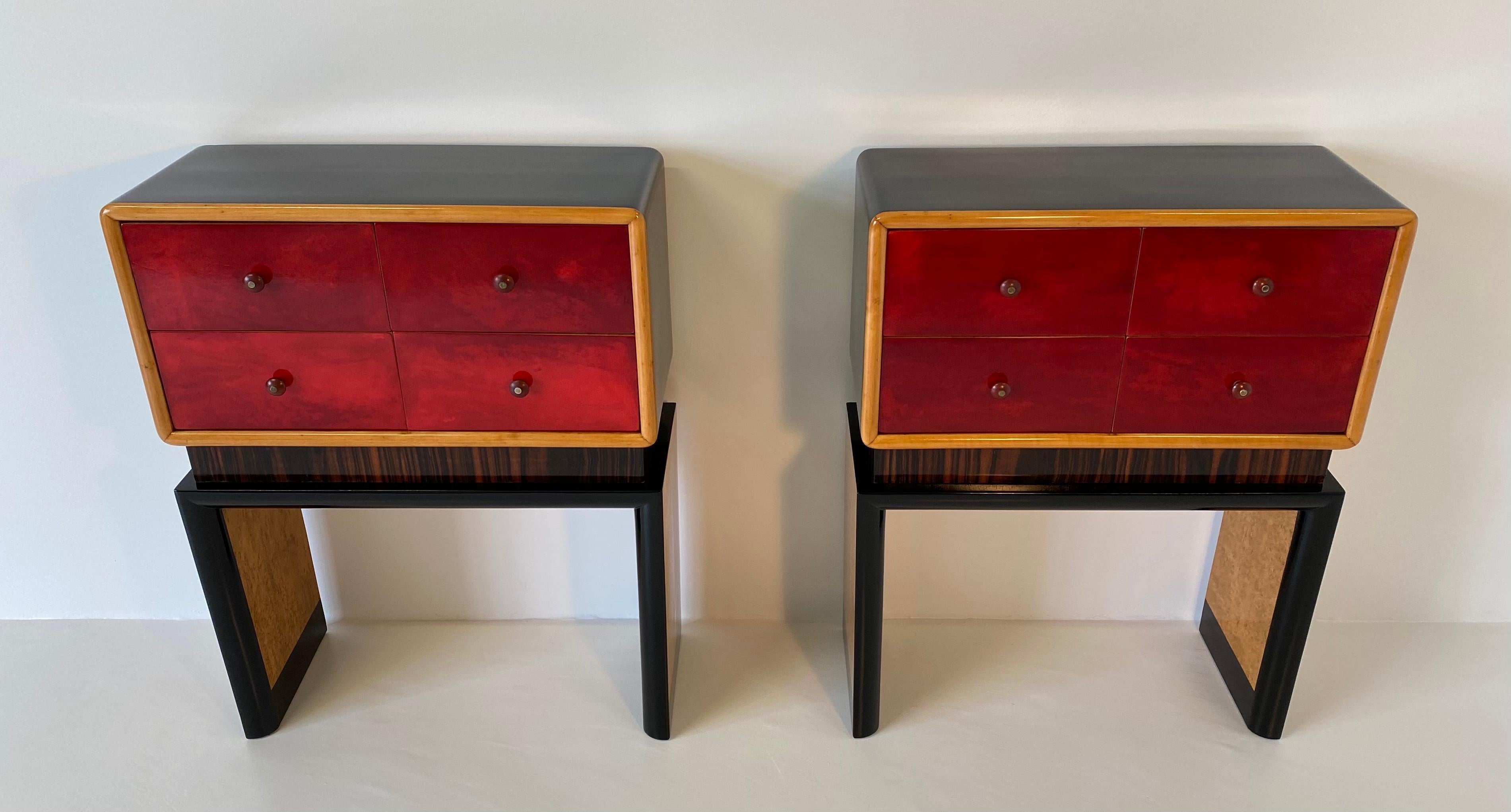These rare and unique twin chest of drawers were produced in Italy in the 1950s.
The front of the drawers are covered in cherry red parchment while the base is in maple burl.
The structure and profiles are black lacquered and the central column is