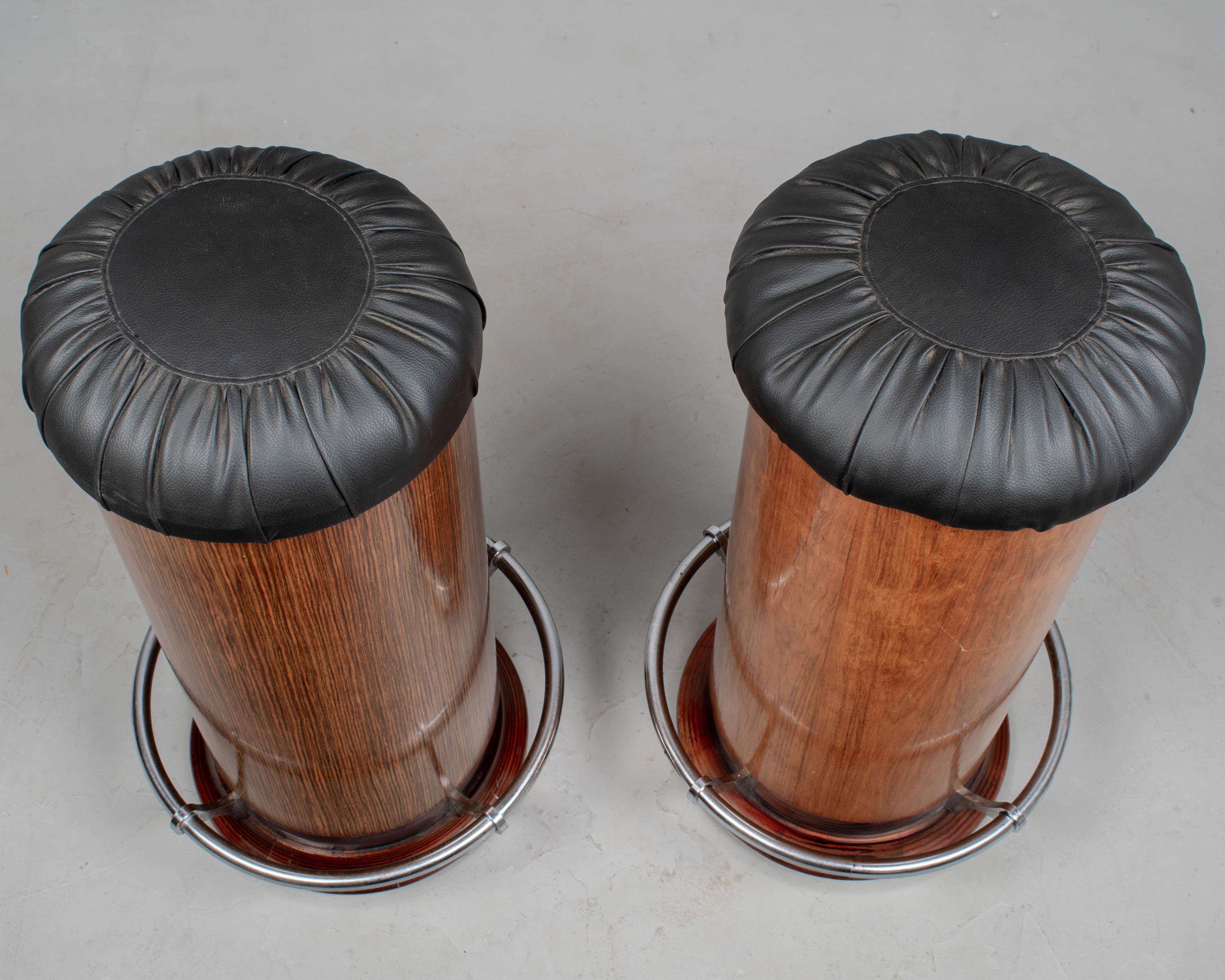 Un par de taburetes de bar marinos de estilo Art Déco italiano vintage. Cada uno con asientos de cuero negro y reposapiés tubular cromado, uno es de chapa de caoba y el otro de chapa de macasar.  En buen estado, uno con un ligero arañazo. Alrededor